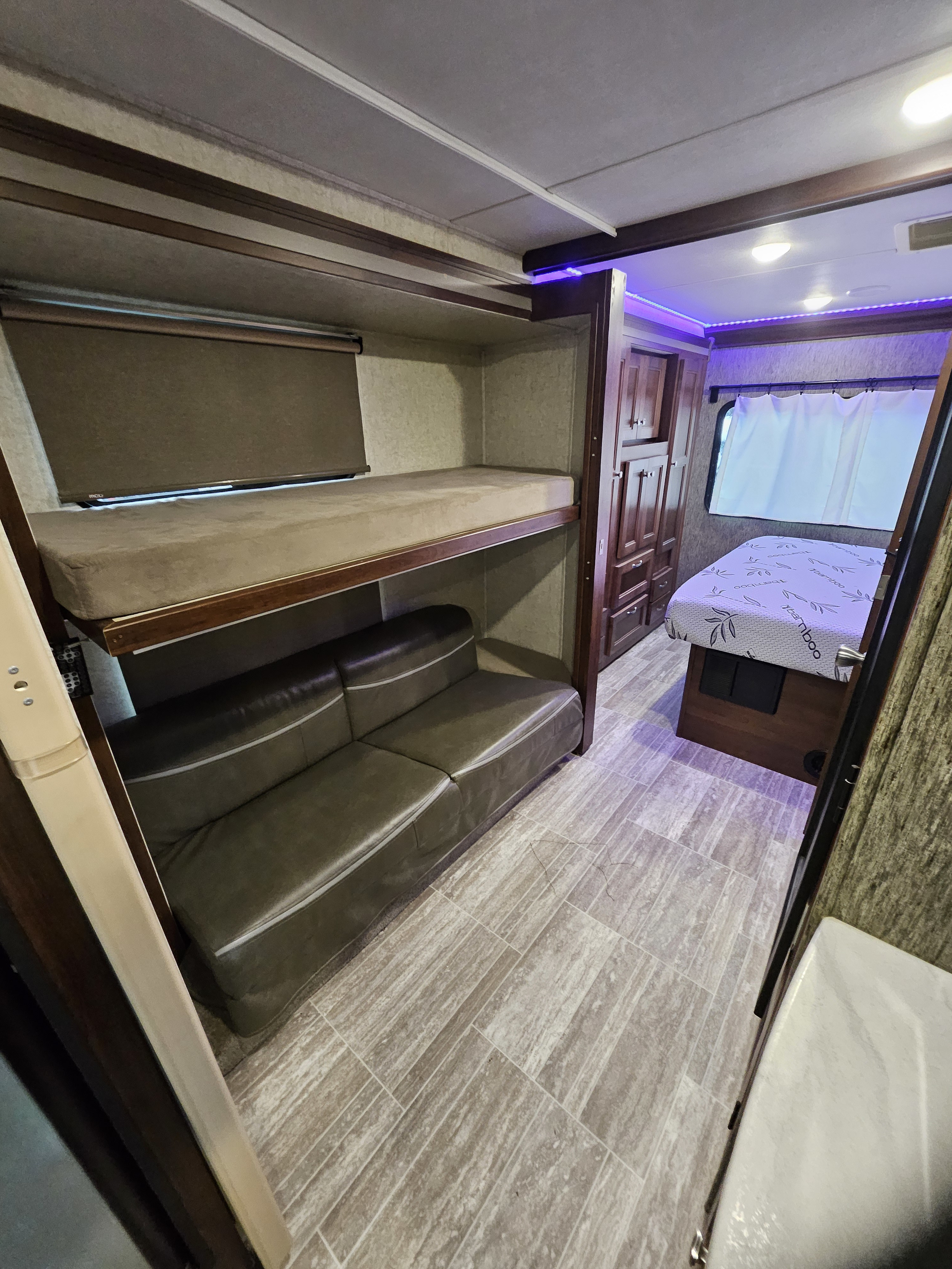 RV rental bunkhouse with bunk beds, a sofa, and a view into the master bedroom with ambient lighting.. Forest River Forester 2018