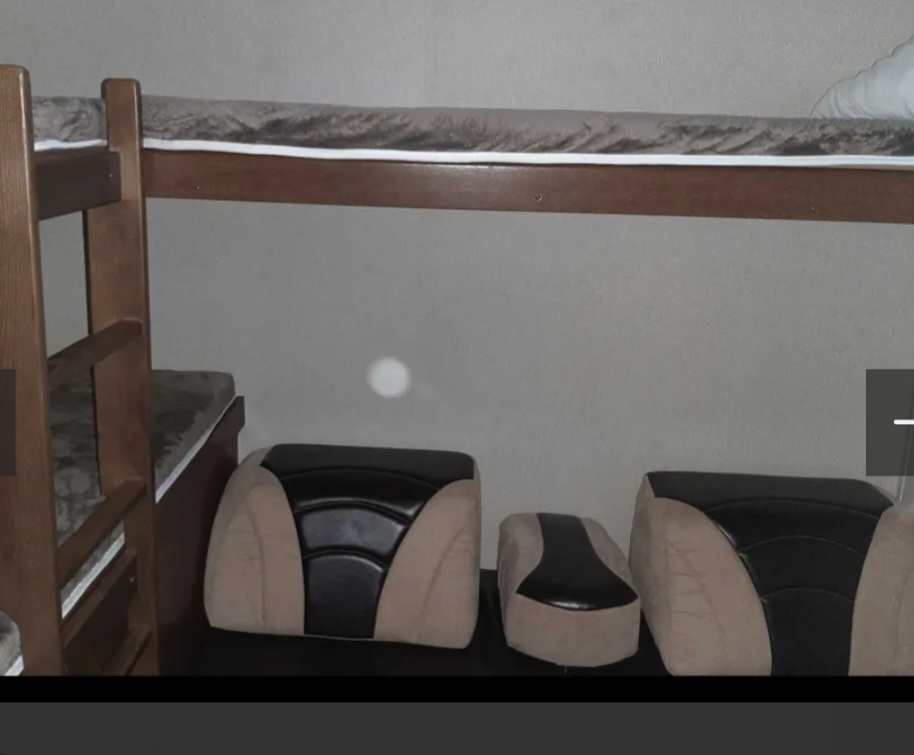 RV rental interior. Wooden bunk beds above modular beige and black RV seating cushions for flexible space.. Avenger ATI 2019