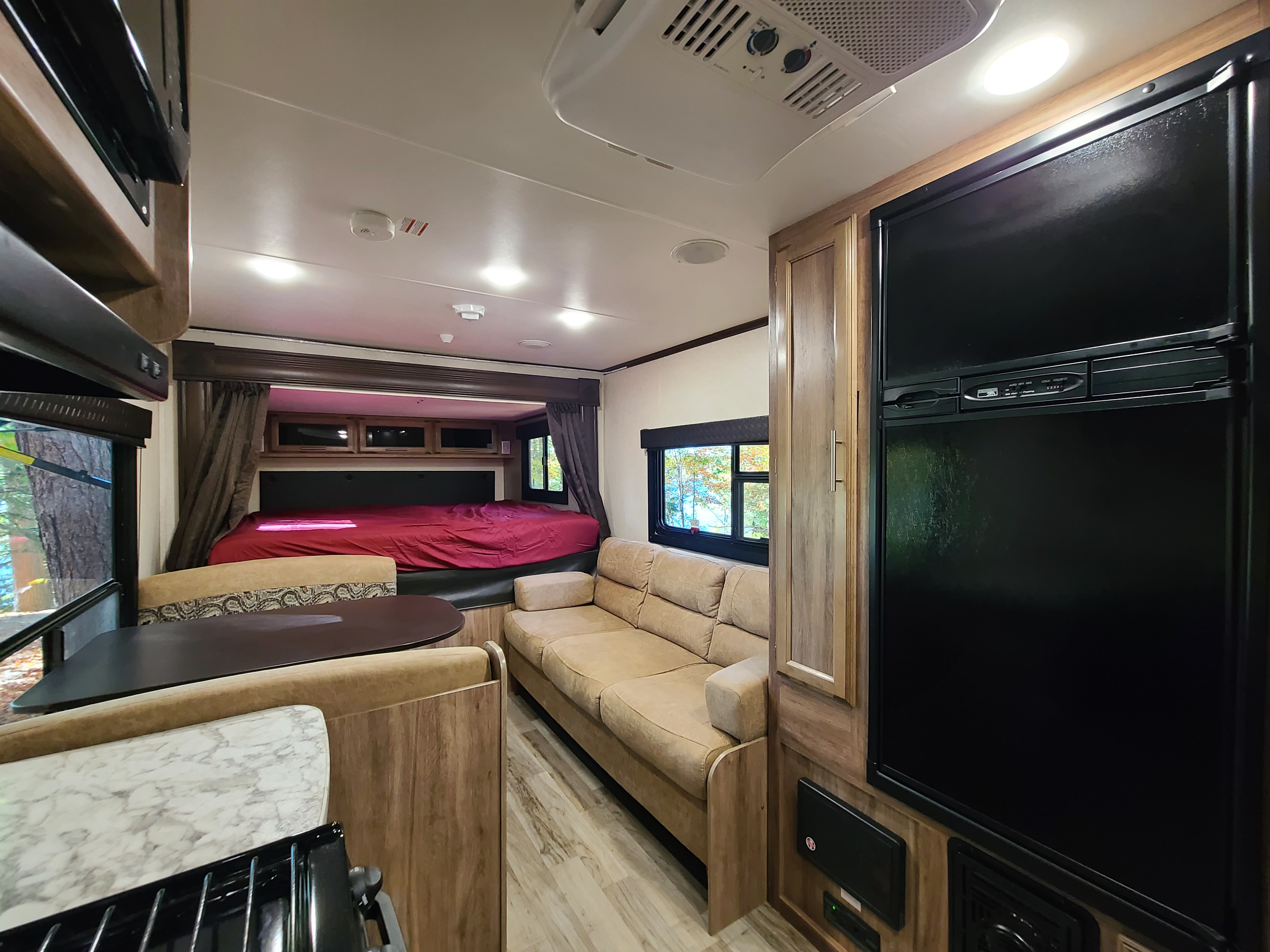 Inside this RV rental: a bright living space with bed, couch, dining booth, fridge, and kitchen. Ready for travel.. Jayco Jay Feather 2018