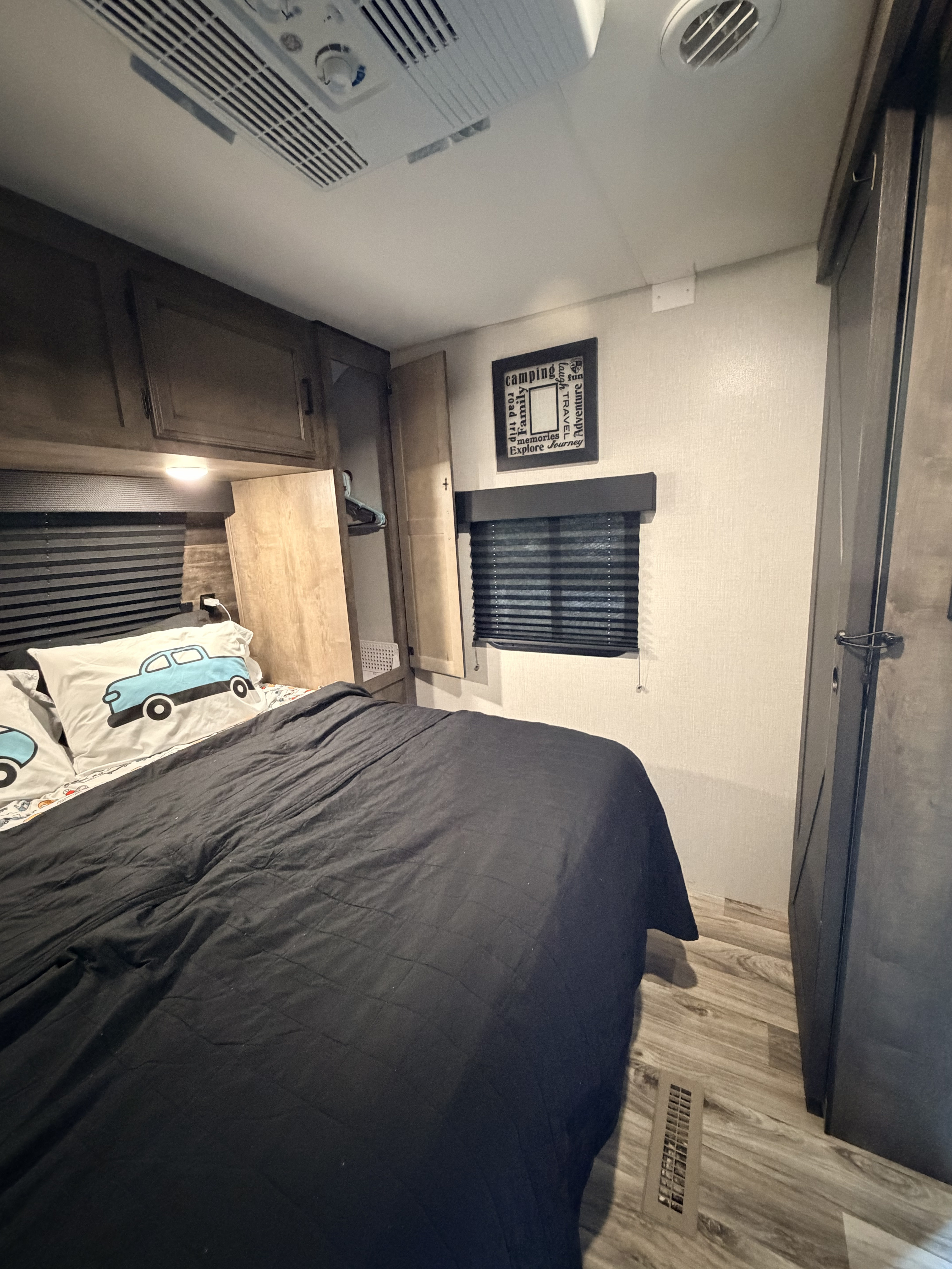 RV rental bedroom: a compact space with a comfy bed, car-themed pillows, overhead cabinets, and AC for travel.. Venture SportTrek ST241VMS 2021