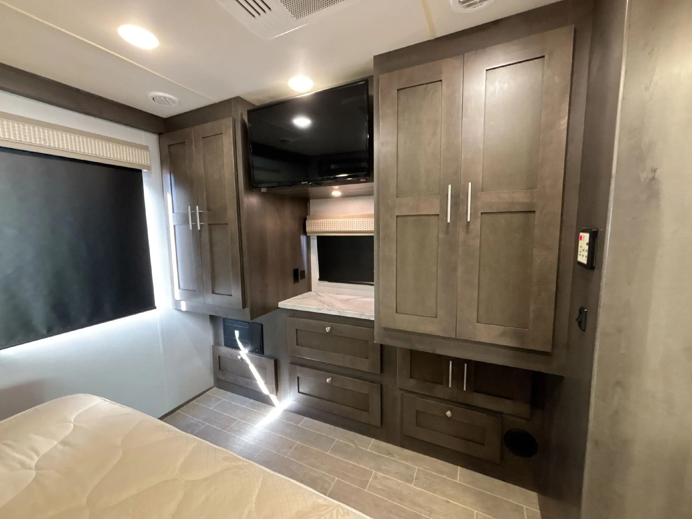 Explore this RV rental's cozy bedroom, complete with a mounted TV, ample storage, and modern built-in cabinetry.. Georgetown GT3 2021