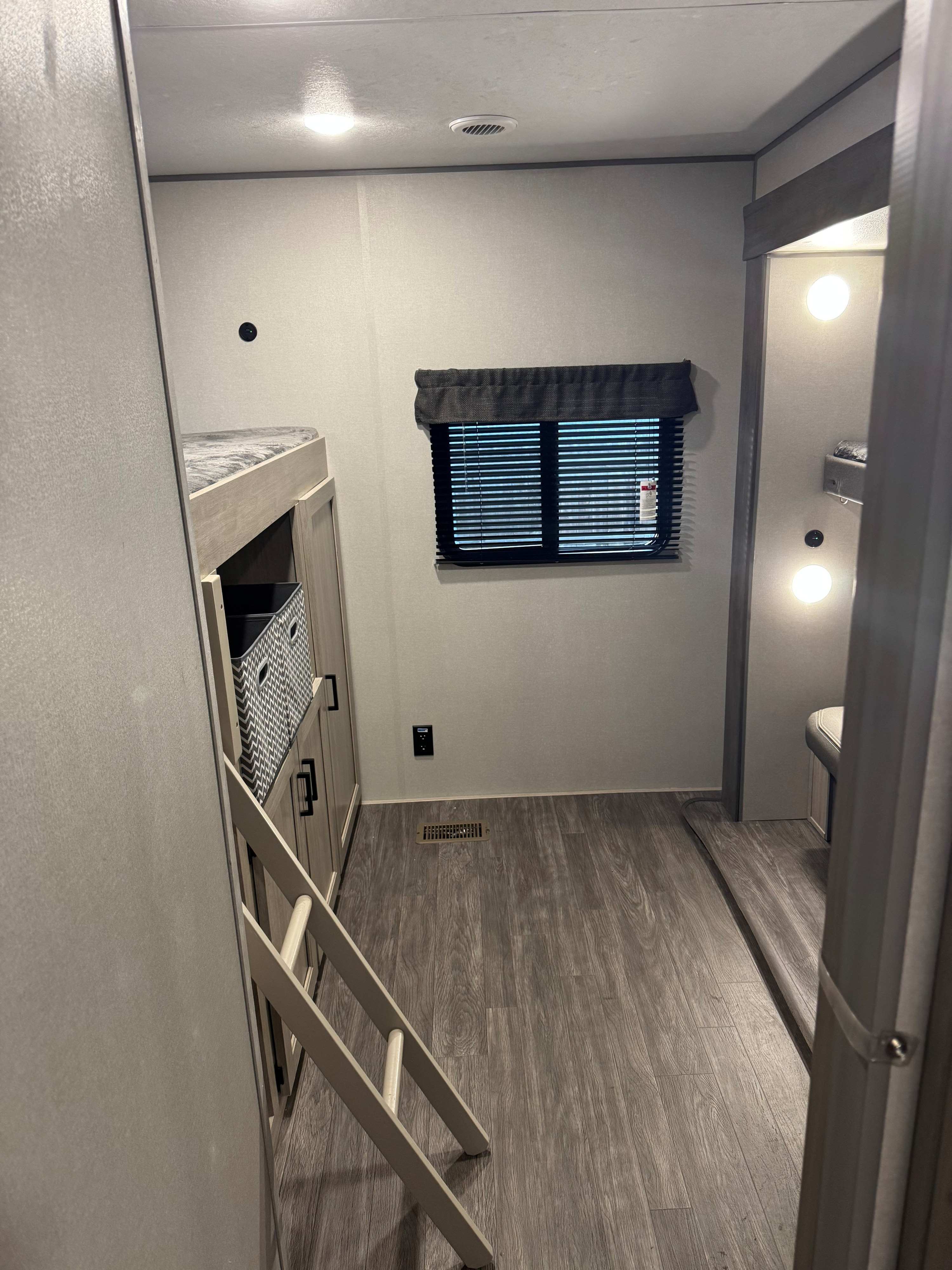RV rental bunkhouse interior: bunk beds with ladder, storage, window, and wood-look floor. Ideal for camper adventures.. Forest River Aurora Aurora 2026