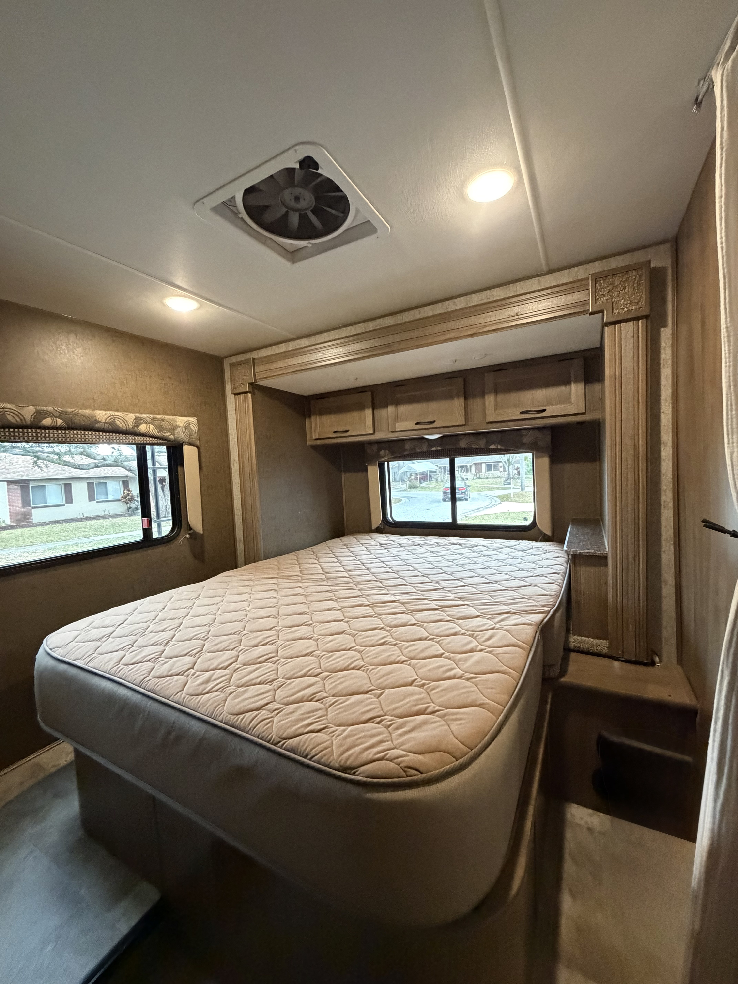 Cozy rv rental bedroom with a quilted mattress, overhead storage, window views, a ceiling fan, and recessed lighting.. Coachmen Freelander 26 RS 2017