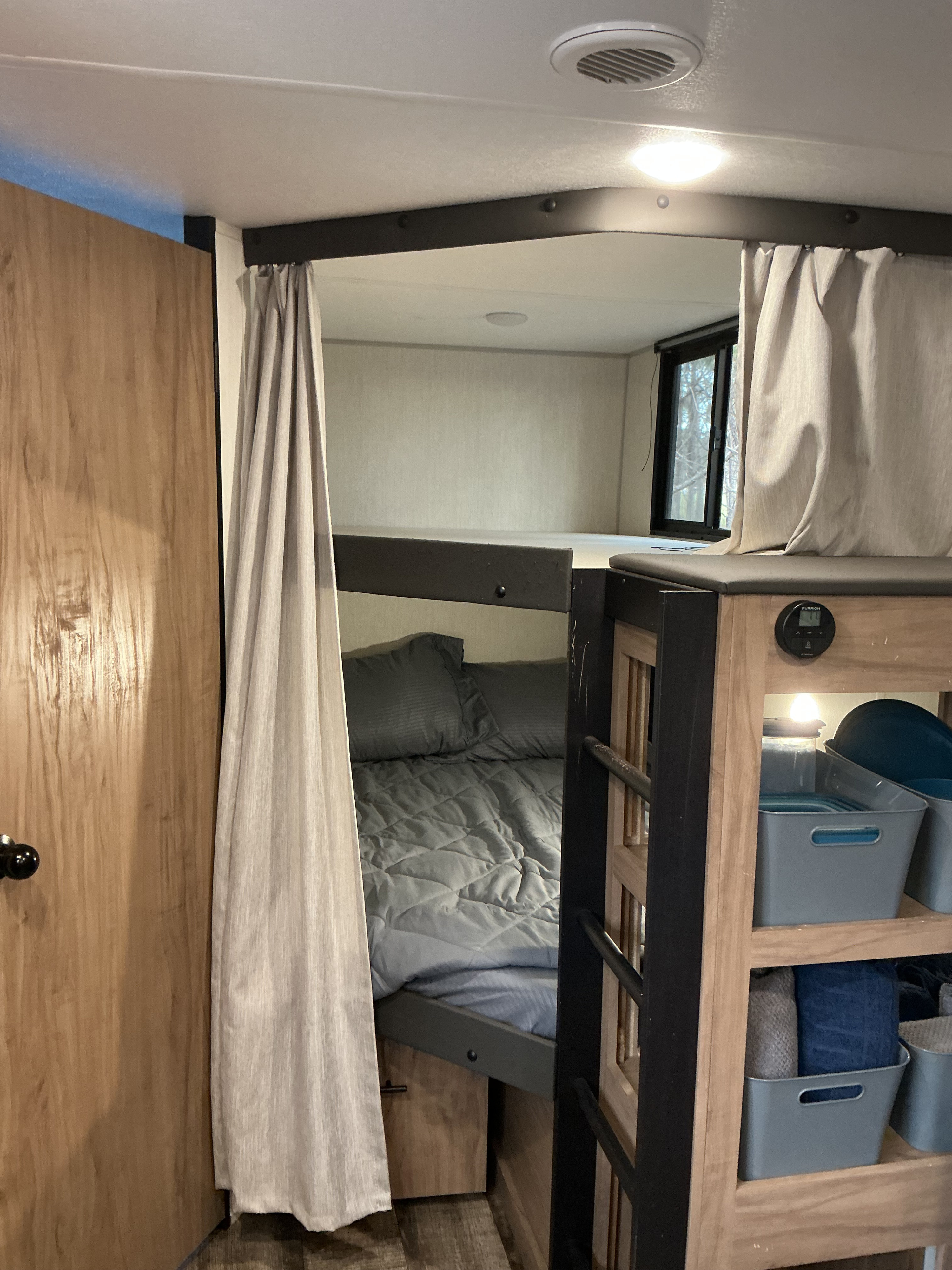 Cozy RV rental bunk beds with privacy curtains, storage, and a built-in ladder for comfortable lodging.. Forest River Campsite Reserve 2025