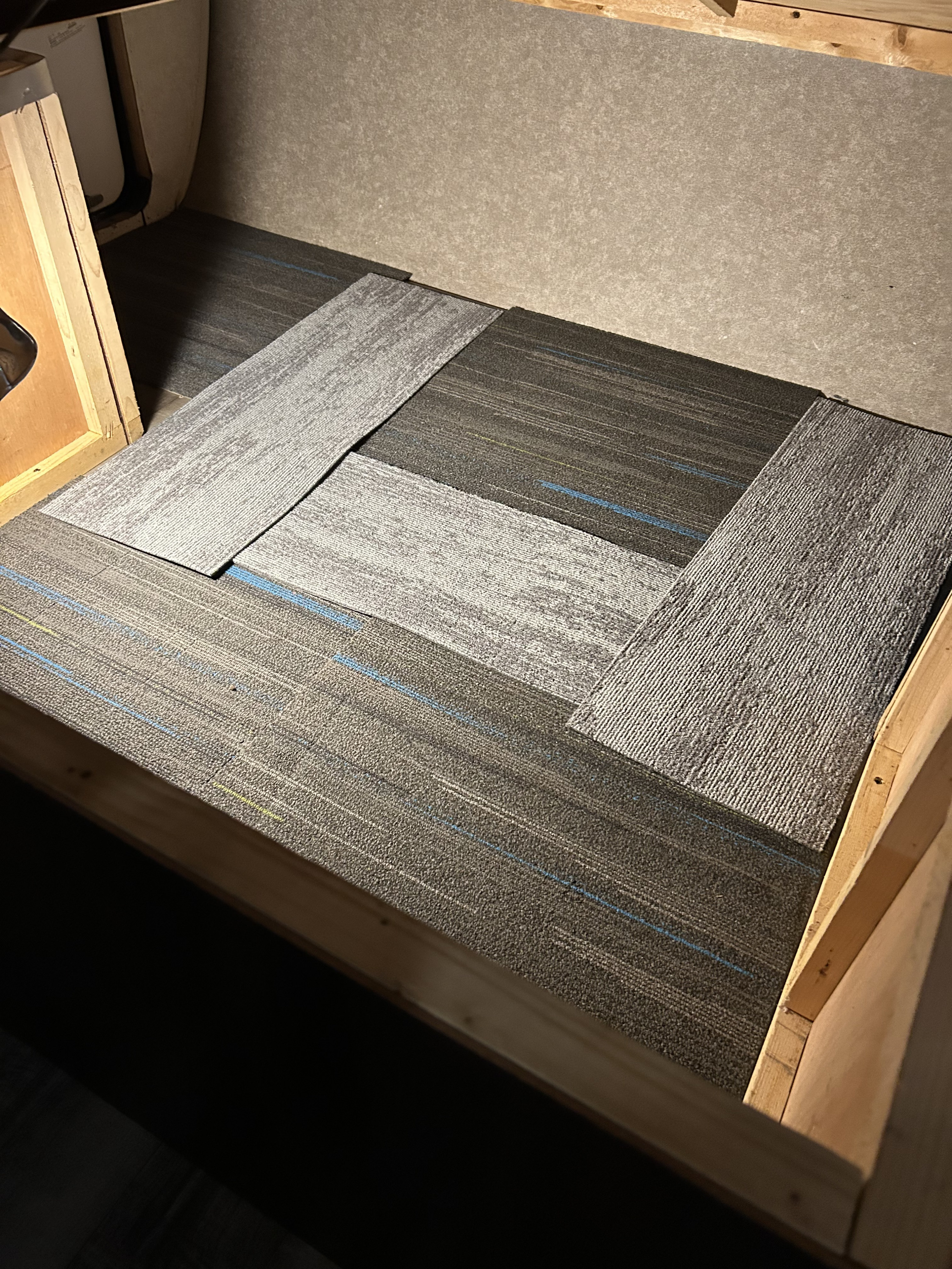 Carpet tiles being installed in an RV rental interior, showing dark and light grey patterns with blue accents.. Jayco Jay Flight SLX 2018