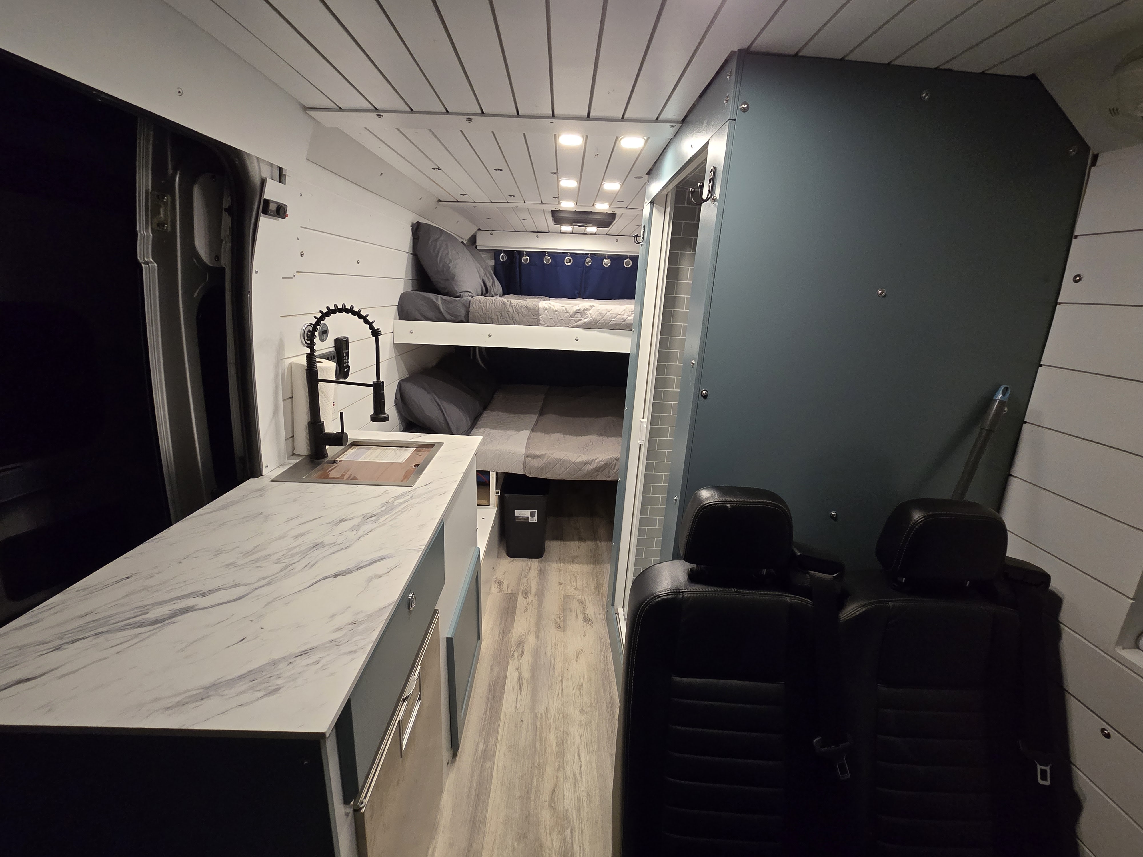 Inside this modern rv rental van: kitchen, bunk beds, & shower enclosure for ultimate road trip comfort.. Other Promaster 2021