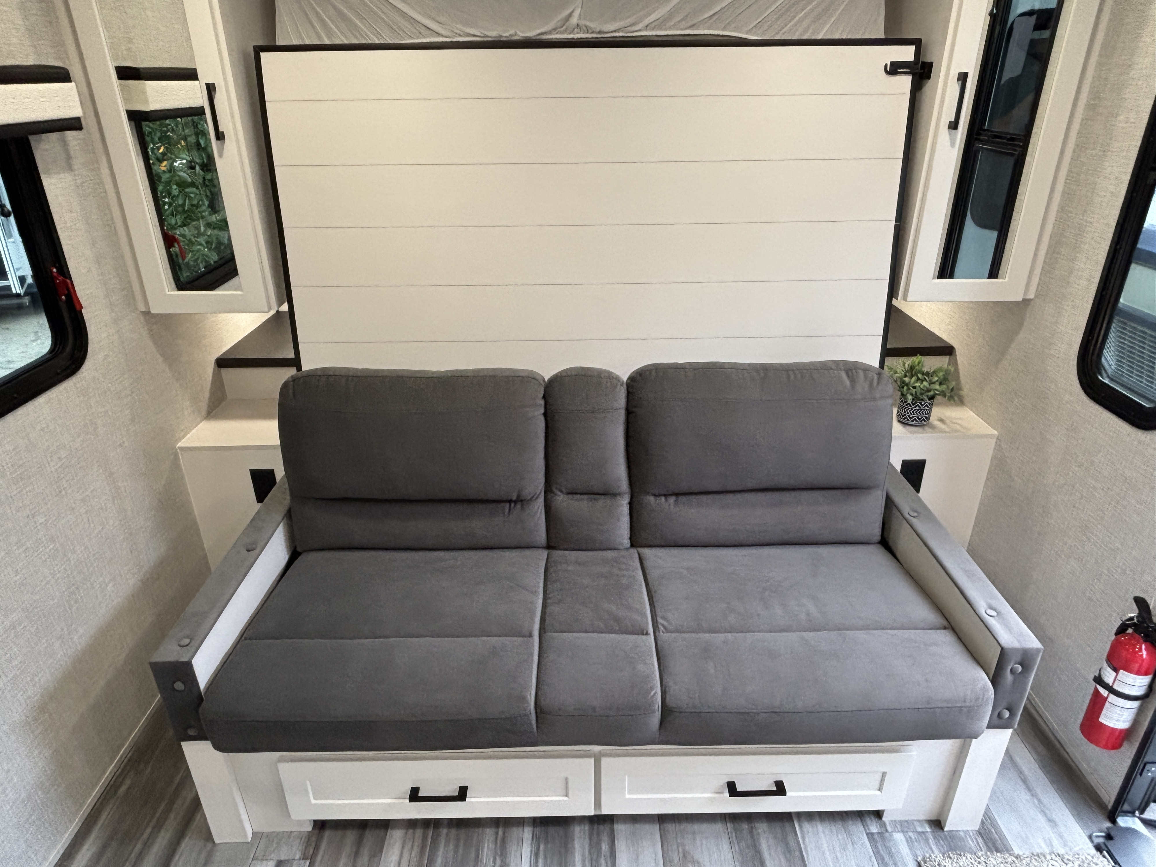 RV rental living space: gray sofa with under-seat storage and a white shiplap-style Murphy bed that folds up.. Jayco JayFeather AIr 2025