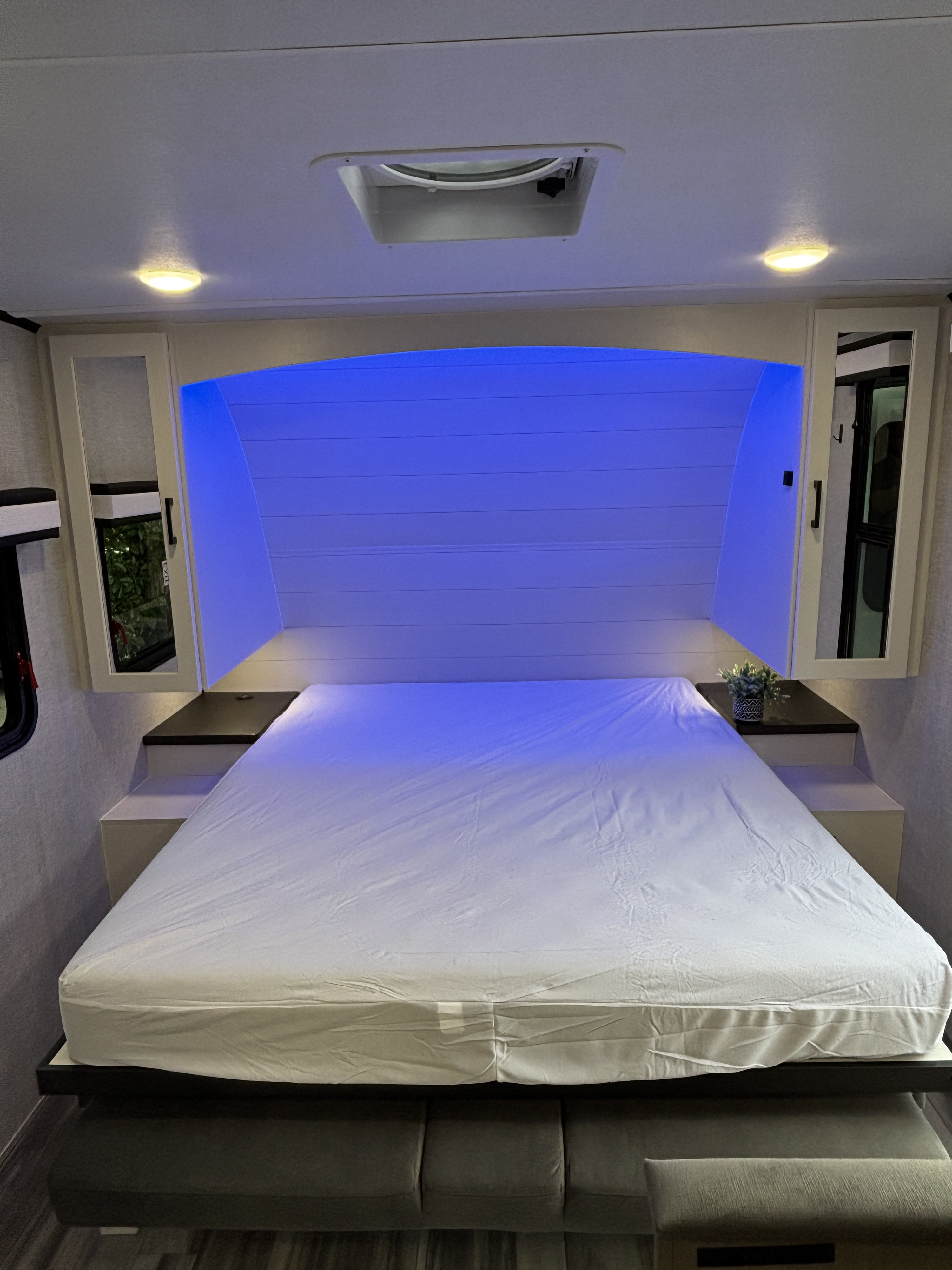RV rental bedroom interior: cozy bed with blue accent lighting, overhead cabinets, and practical storage.. Jayco JayFeather AIr 2025