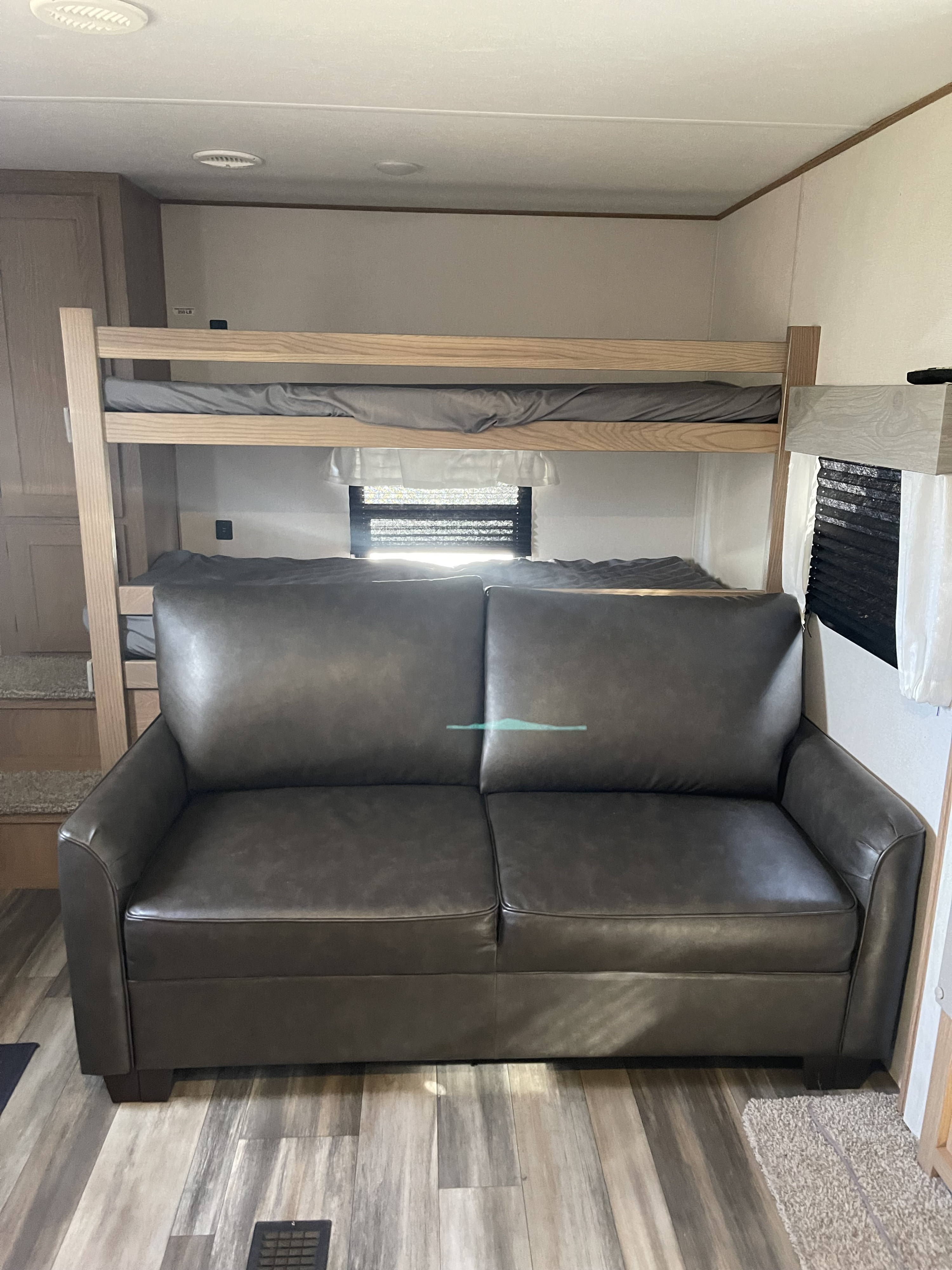 Experience comfort in this RV rental! Features a dark sofa, bunk beds, wood-look floor, and a window for natural light.. Avenger Avenger Trailer 2022