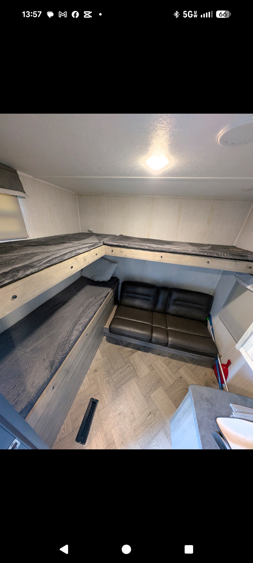 RV rental interior features L-shaped bunk beds with grey bedding, black sofa, and light wood-look herringbone flooring.. Forest River Palomino Puma 2021