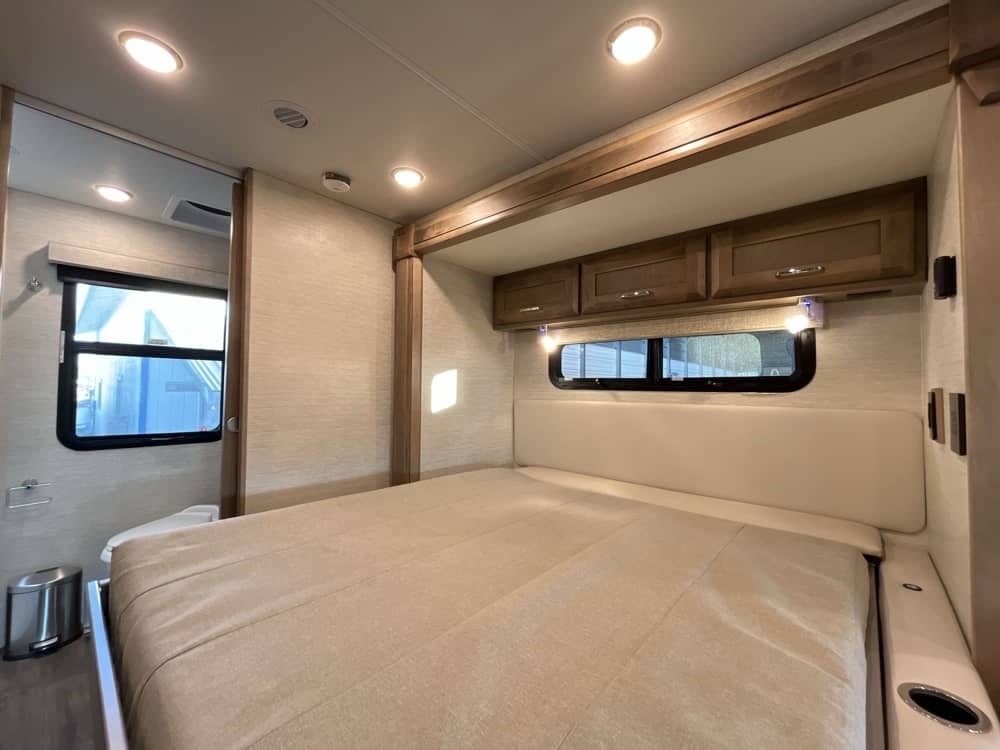 Comfortable RV rental bedroom interior featuring a large bed, overhead cabinets, and bright lighting.. Wayfarer Wayfarer Motorhome 2021