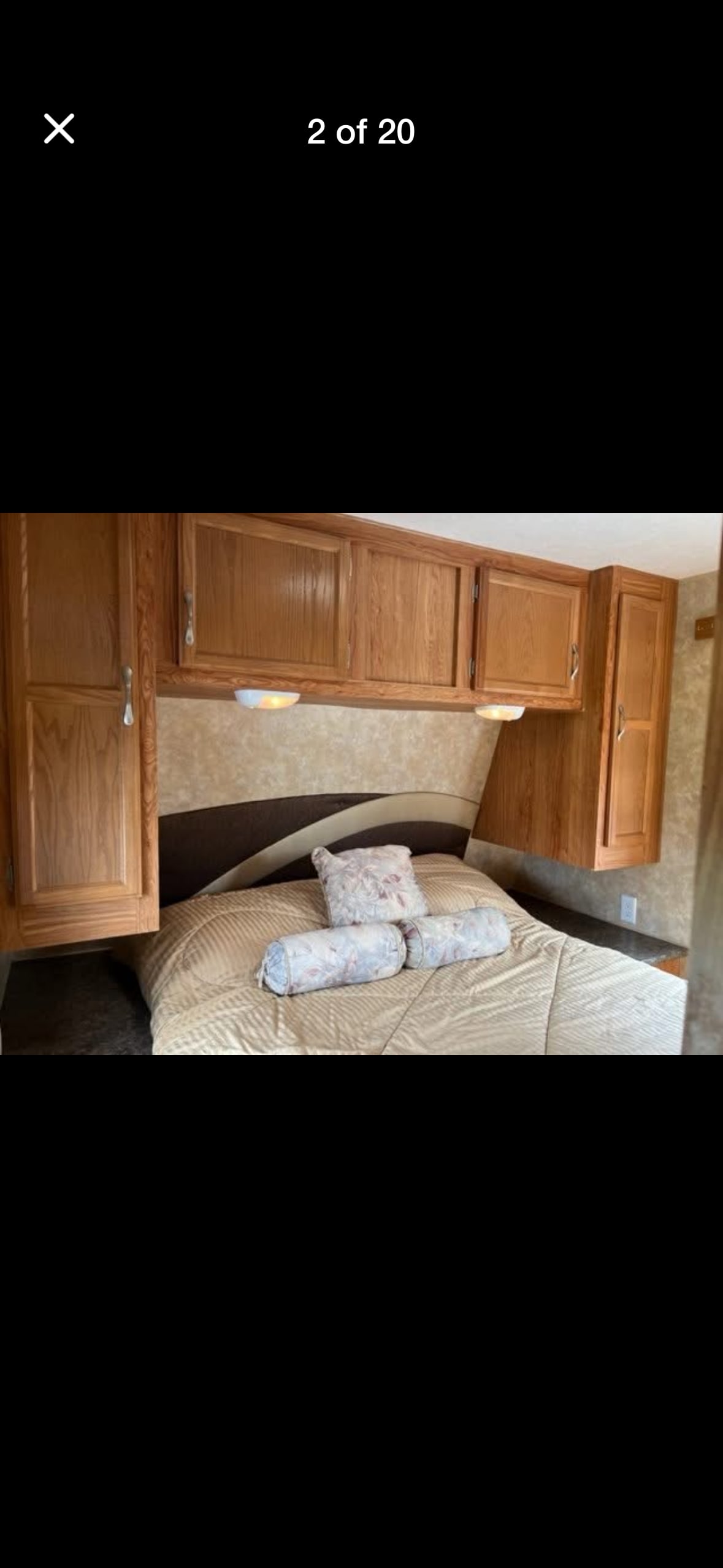 Cozy RV rental bedroom featuring wooden storage cabinets above a comfortable bed with decorative pillows and wall-mounted lights.. Jayco Jay Flight G2 2010