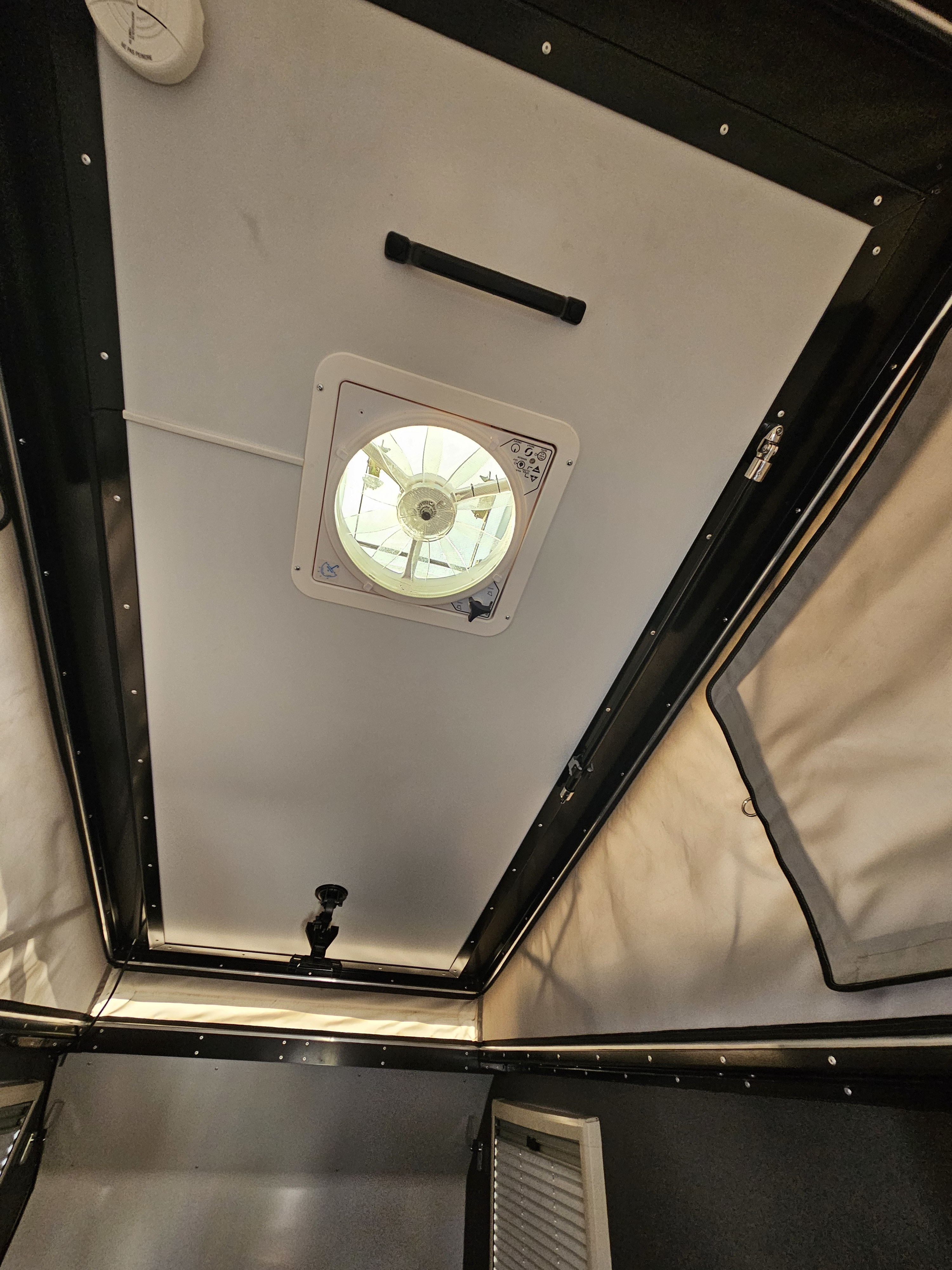 Inside an RV rental: Looking up at the pop-top camper ceiling with a vent fan, grab handle, and smoke detector.. Mission Overland Mission Overland Trailer 2022