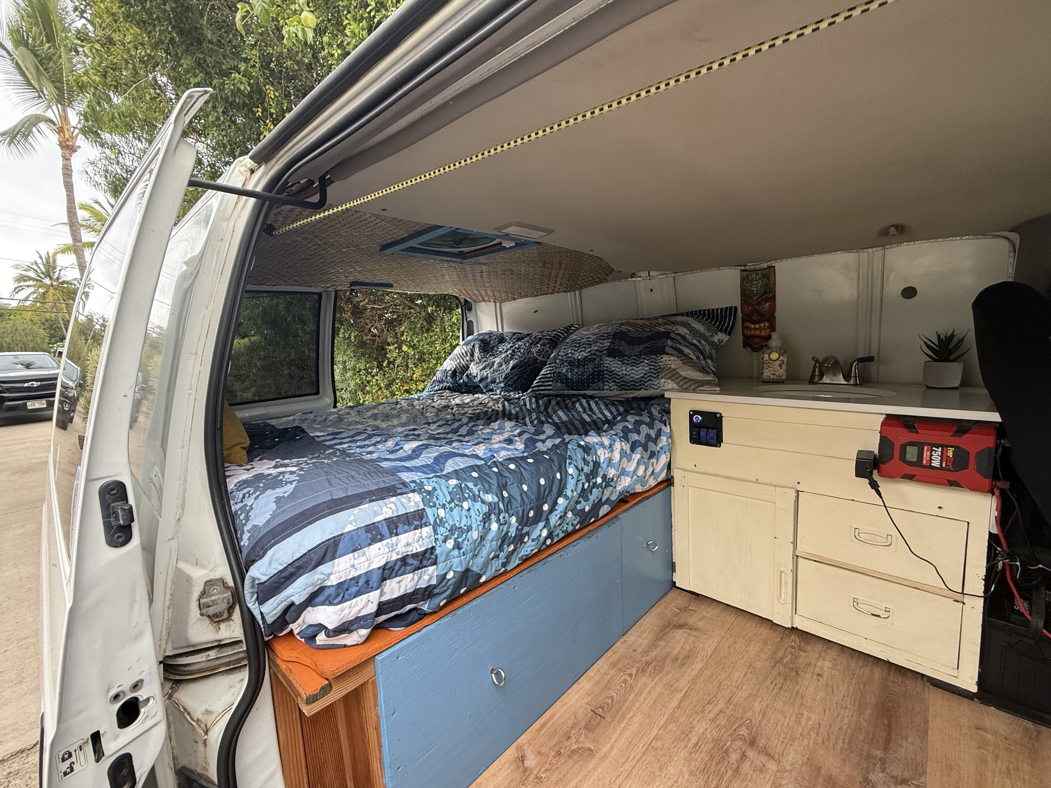 This cozy RV rental features a custom campervan interior with a bed, kitchenette, and wood floor, perfect for mobile living.. Chevrolet Other 2005
