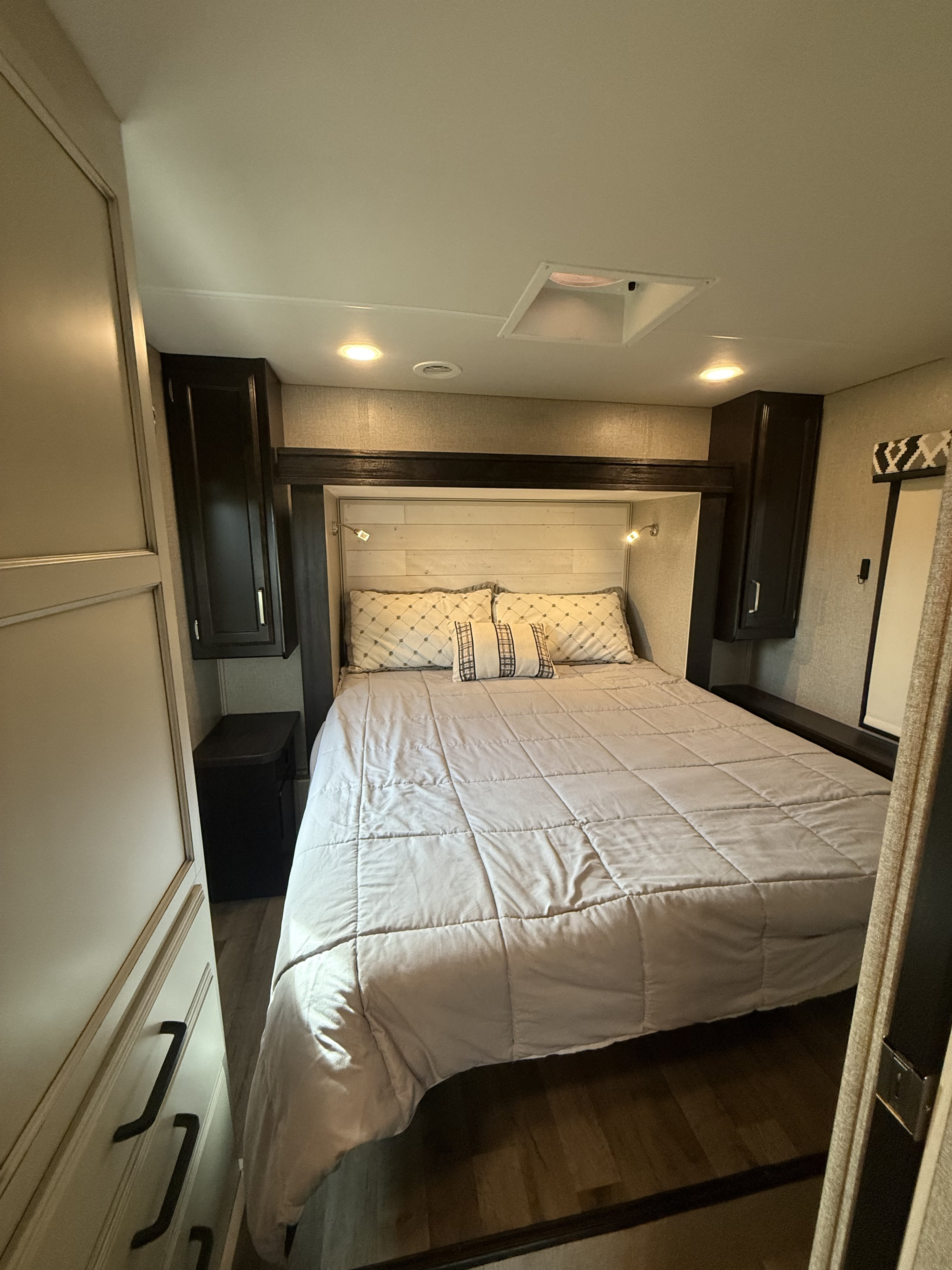 Cozy RV rental bedroom with queen bed, overhead storage, and wood-look floors, ready for a comfortable adventure.. Jayco Greyhawk 2021