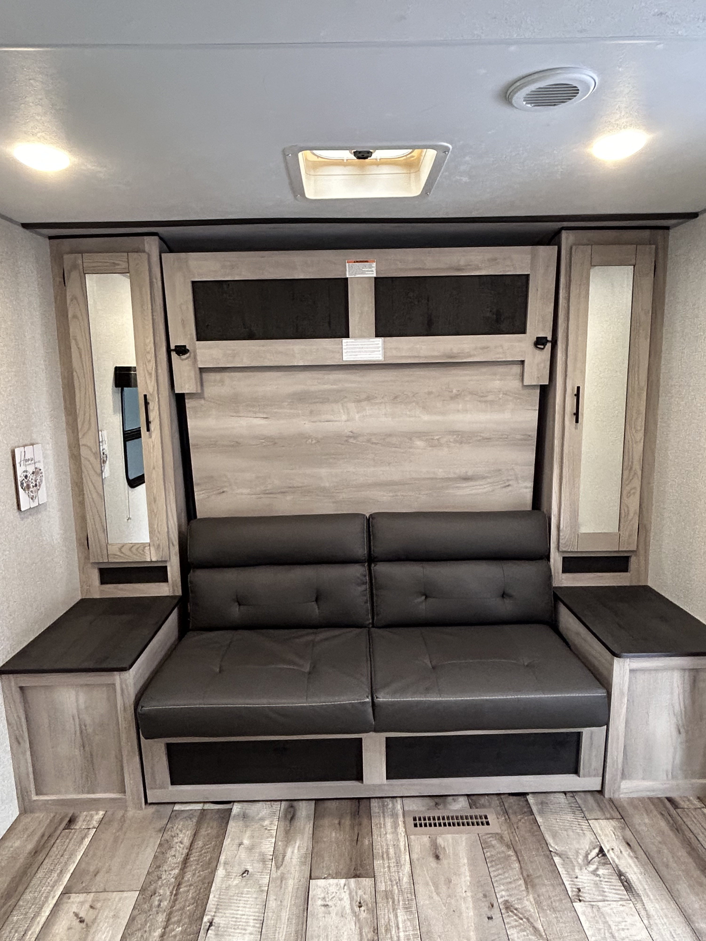 RV rental: Interior with a dark gray sofa beneath a folded Murphy bed, surrounded by cabinets, and wood-look floor.. KZ Connect C231BHKSE 2023