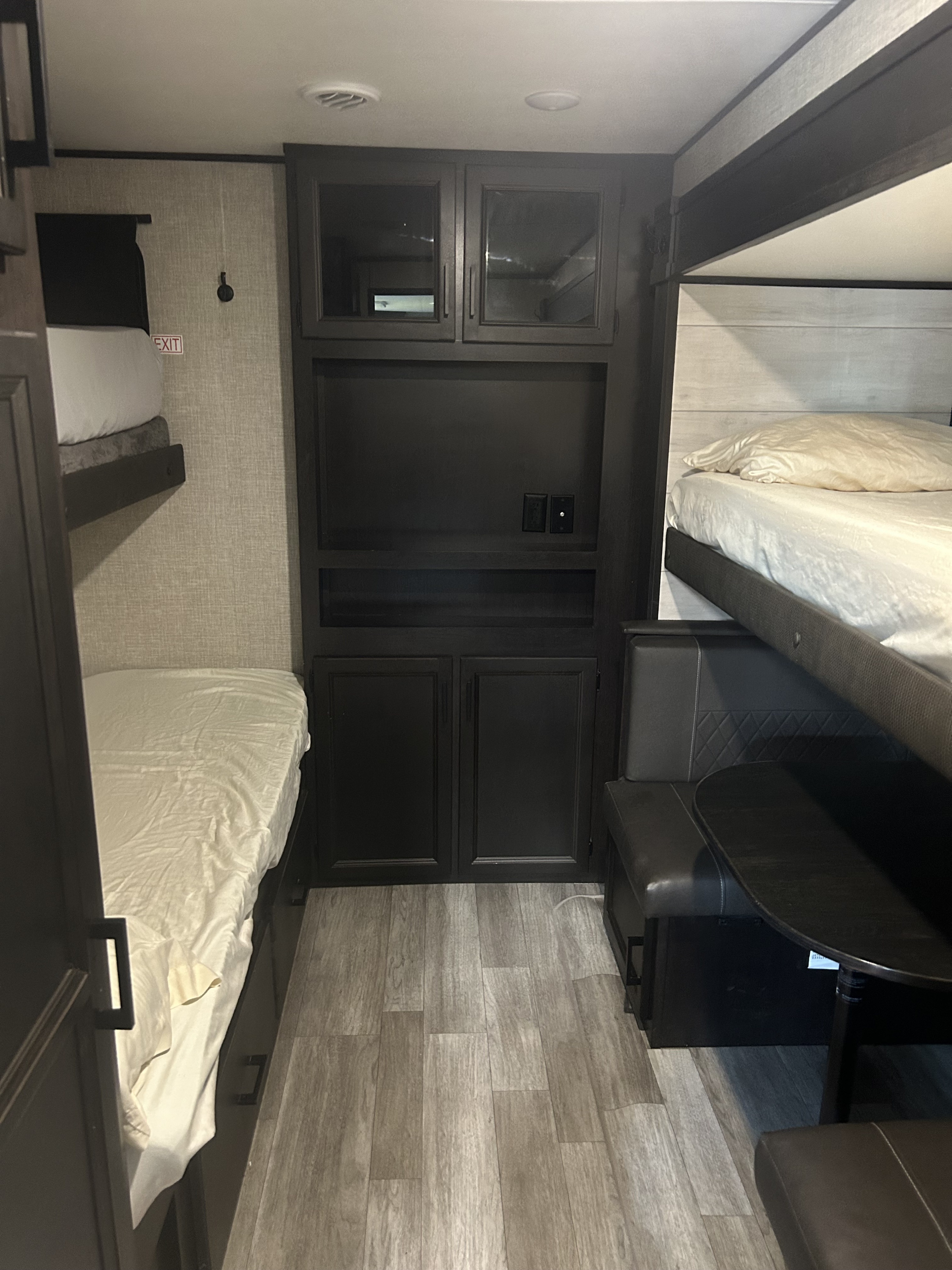 RV rental bunkhouse featuring twin bunk beds, a dark wood storage/entertainment unit, and a compact dinette seating area.. Jayco Jay Flight 2022