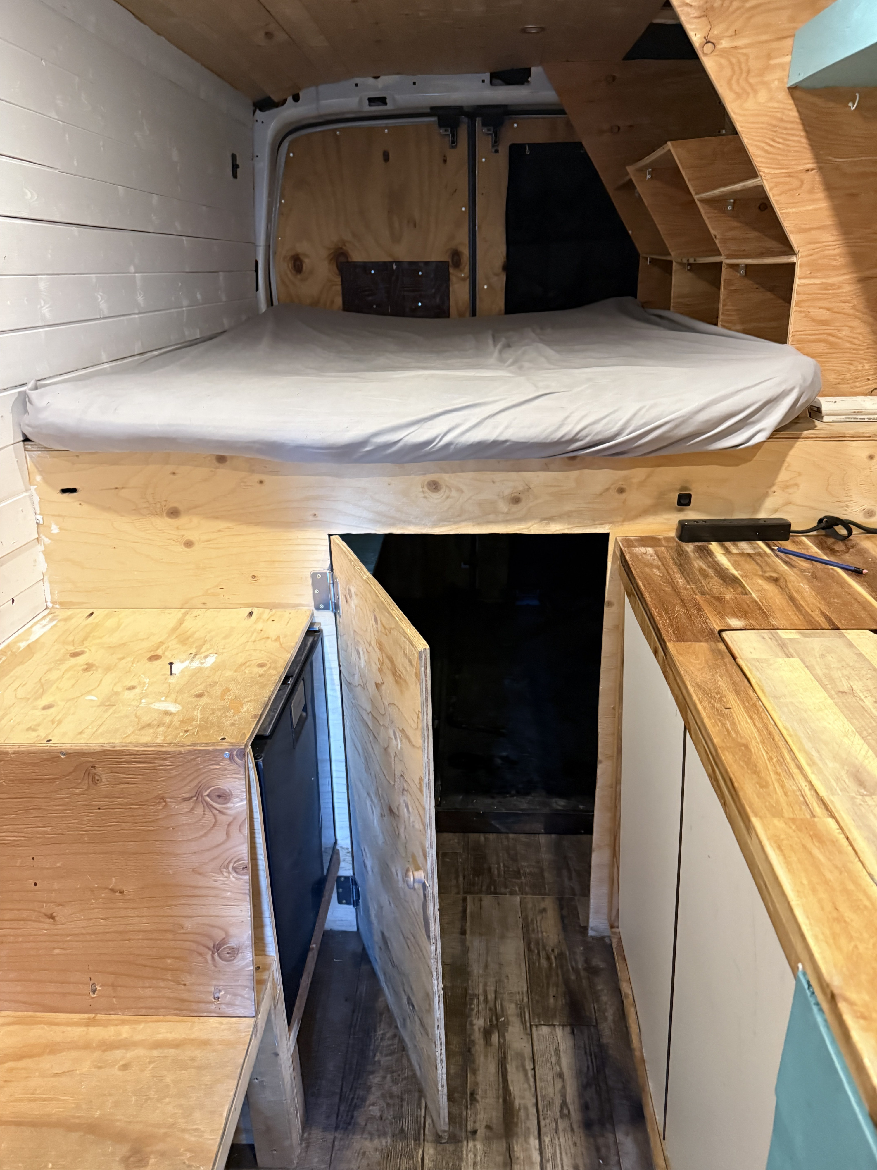 RV rental: Converted van interior featuring a comfortable bed, smart built-in storage, & compact kitchen amenities.. Ford Transit 2021