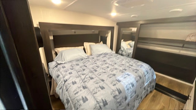 Comfortable RV rental bedroom featuring a blue patterned bed, dark headboard, and mirrored closets.. Forest River Sabre 2025