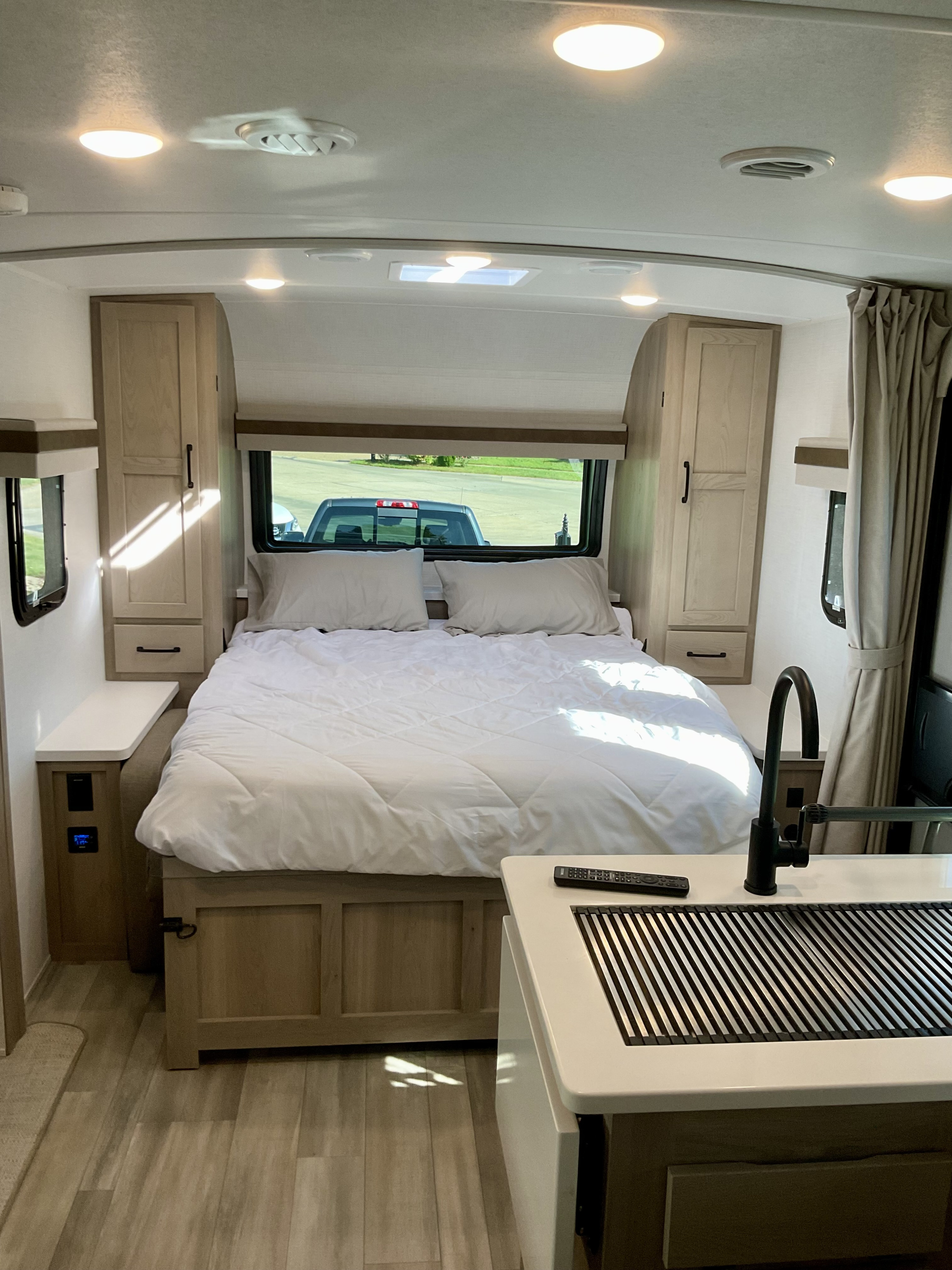 Cozy, modern RV rental bedroom with light wood tones, bright lighting, and integrated kitchenette for a compact, inviting space.. Forest River Rockwood Mini Lite 2024