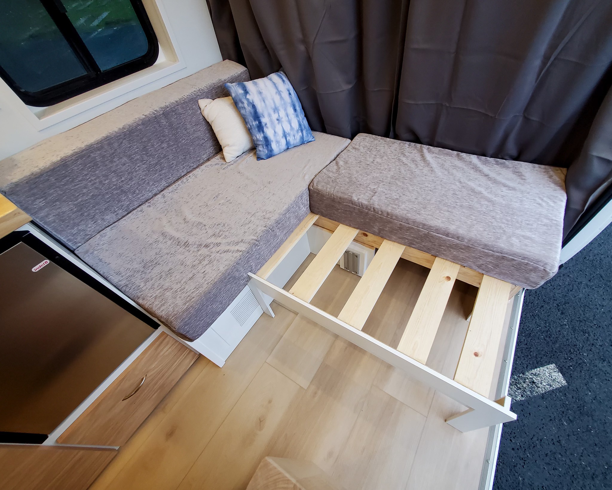 Versatile RV rental interior with L-shaped seating, pull-out bed frame, and built-in fridge for comfort.. Ram Pro master 3500 2015