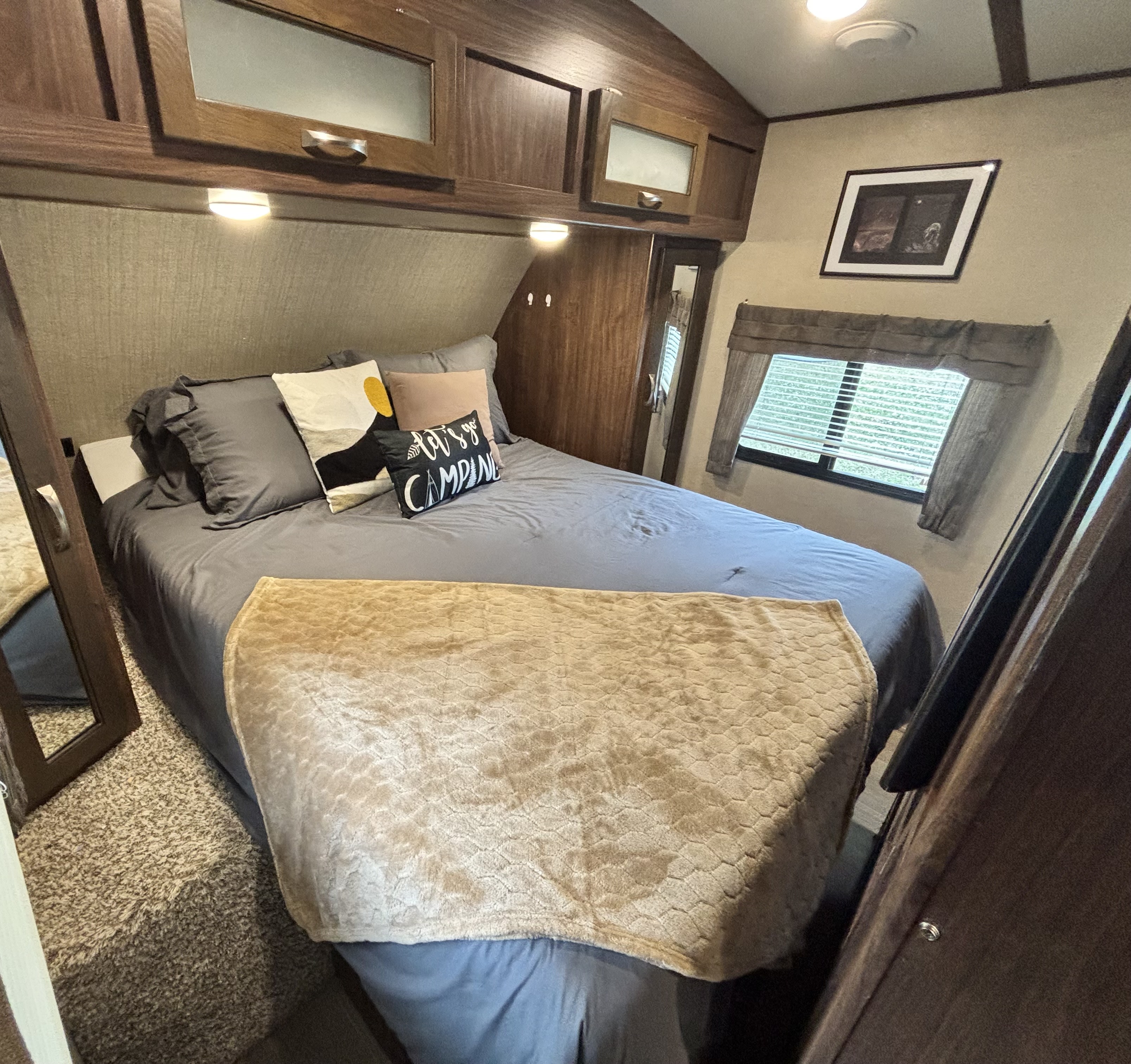 Cozy RV rental bedroom features a comfortable bed, overhead cabinets, window, and inviting decor.. Dutchmen Aerolite 27RBSS 2017