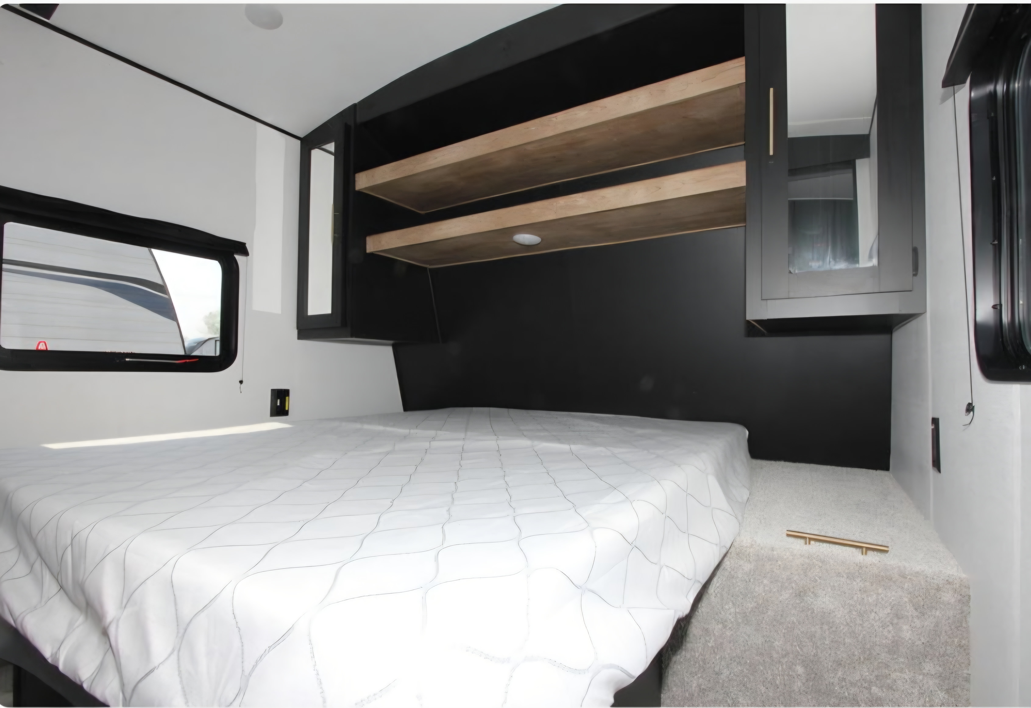 RV rental bedroom with a clean bed, window, overhead wooden shelves, and mirrored storage cabinet.. Keystone RV Springdale 2023