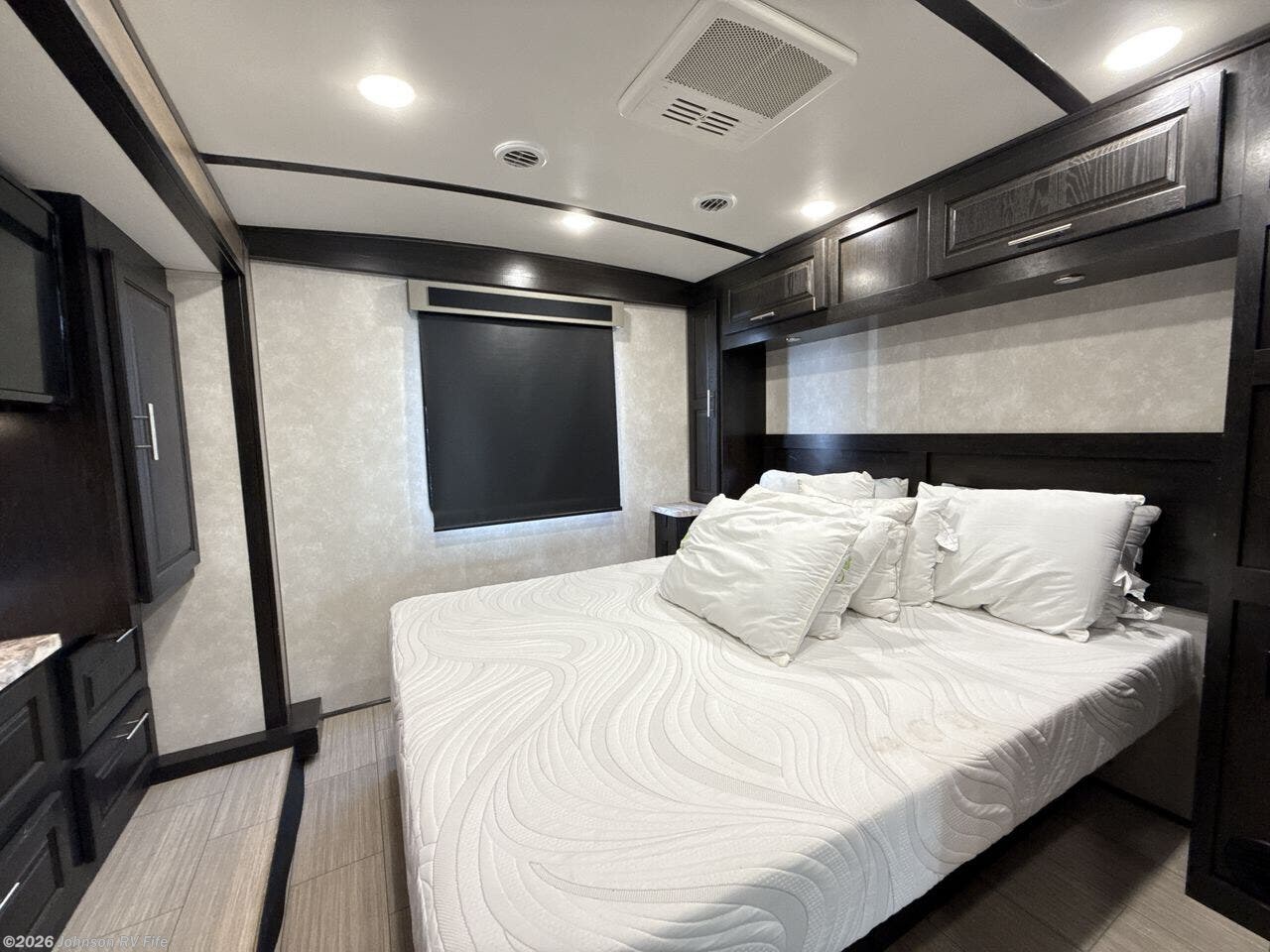 Spacious RV rental bedroom with a large bed, dark wood decor, AC, and window for comfortable accommodations.. FR3 FR3 Motorhome 2022