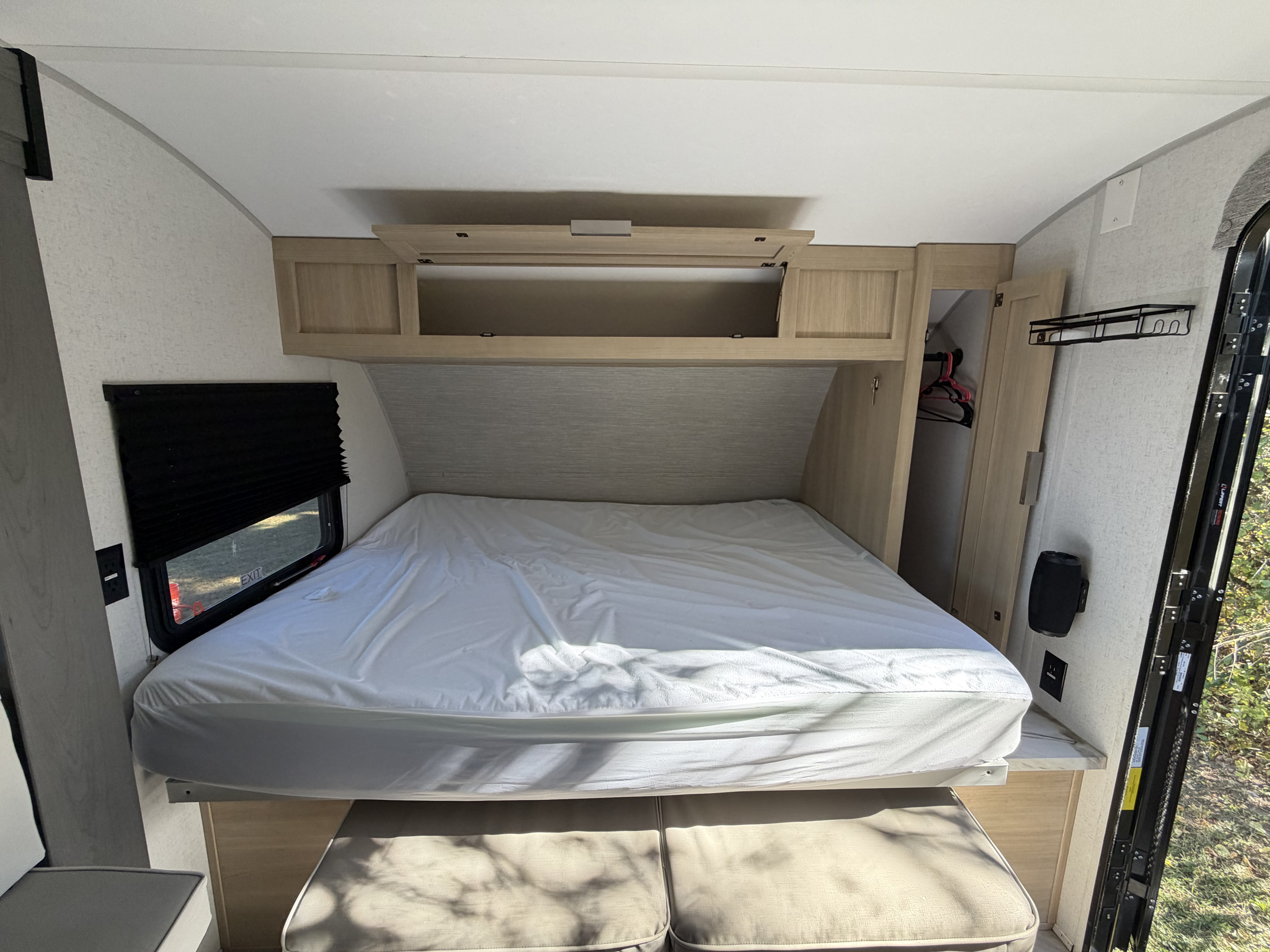 Cozy RV rental bedroom featuring a bed, storage cabinets, window with shade, and closet space for your next adventure.. Forest River Wildwood FSX 2023