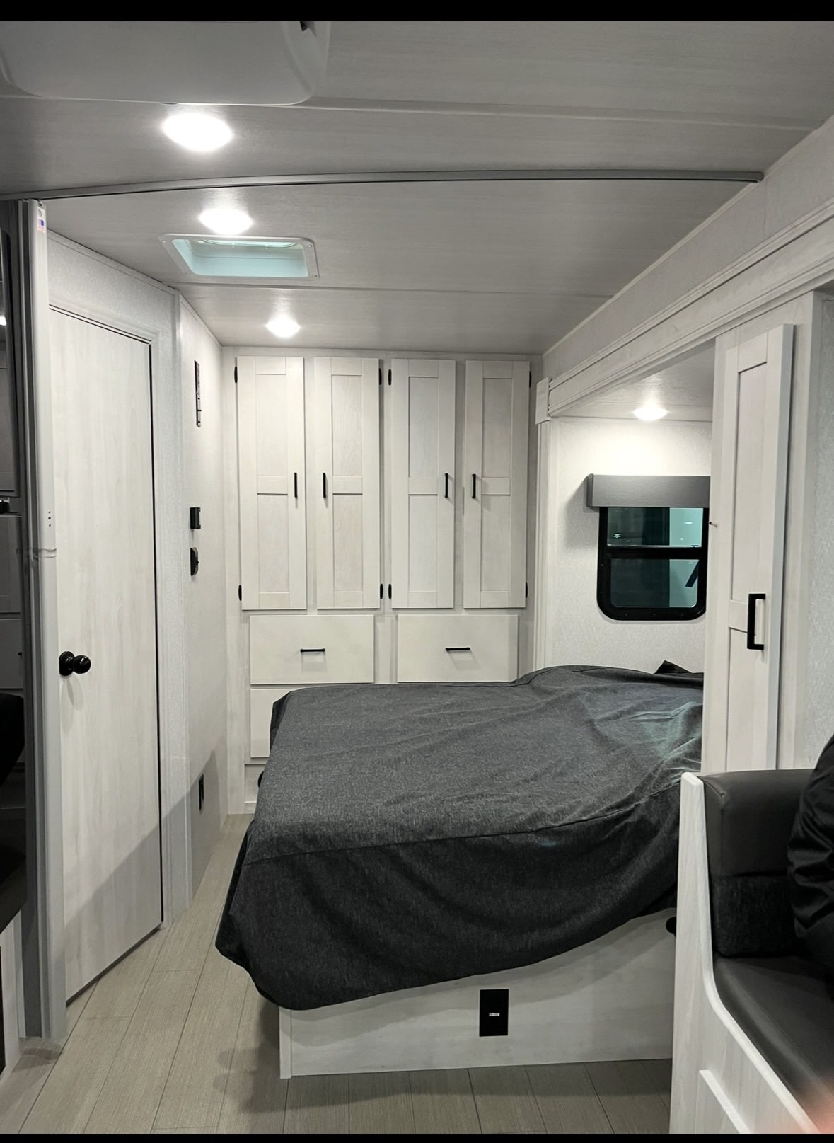 RV rental interior: A bright, modern bedroom featuring a bed, ample storage cabinetry, and a window for comfortable travel.. Forest River East to West Entrada 24FM 2023