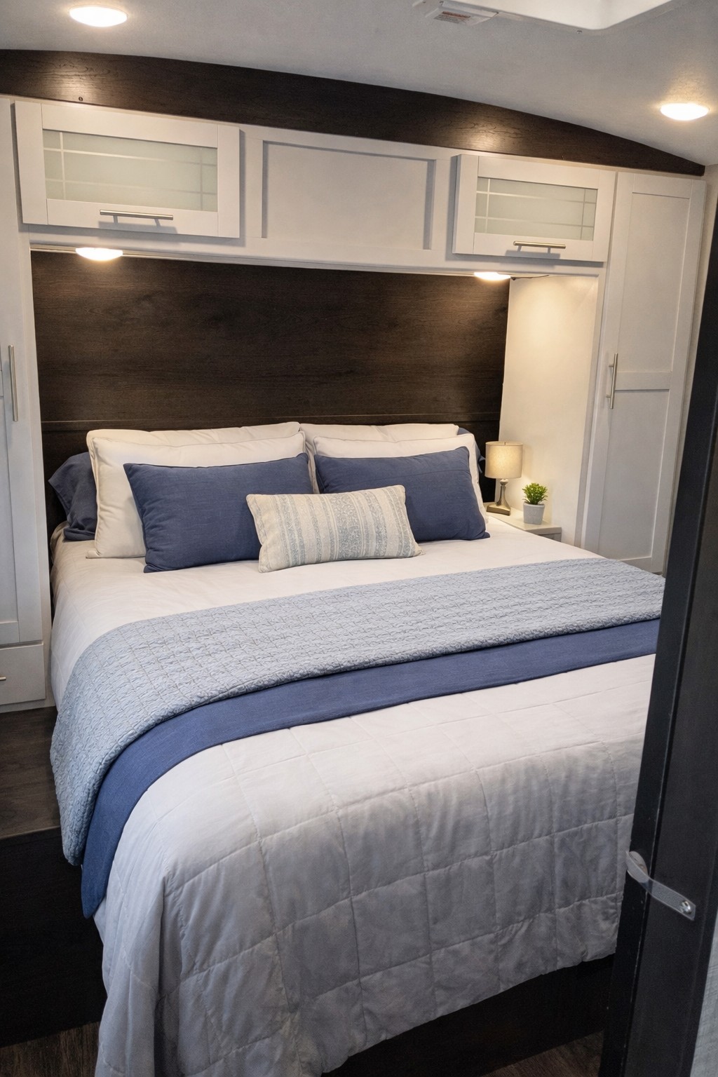 Comfortable RV rental bedroom with a queen bed, blue and white bedding, built-in storage, and ambient lighting.. Keystone RV Bullet Premier Ultra 2021