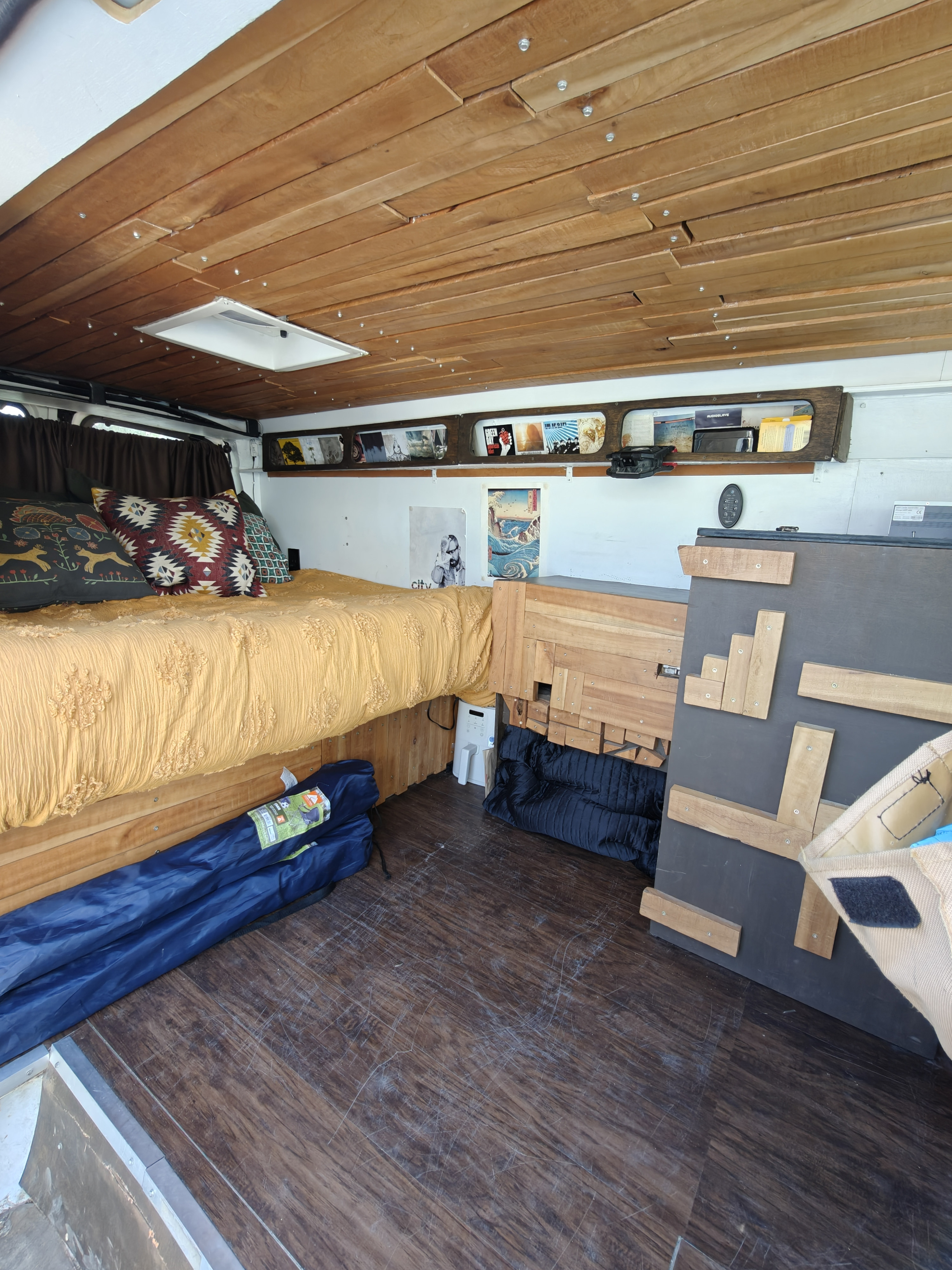 An rv rental camper van interior featuring a cozy bed, wooden slatted ceiling with skylight, and built-in storage.. Chevrolet CHEVY EXPRESS 1500 2004