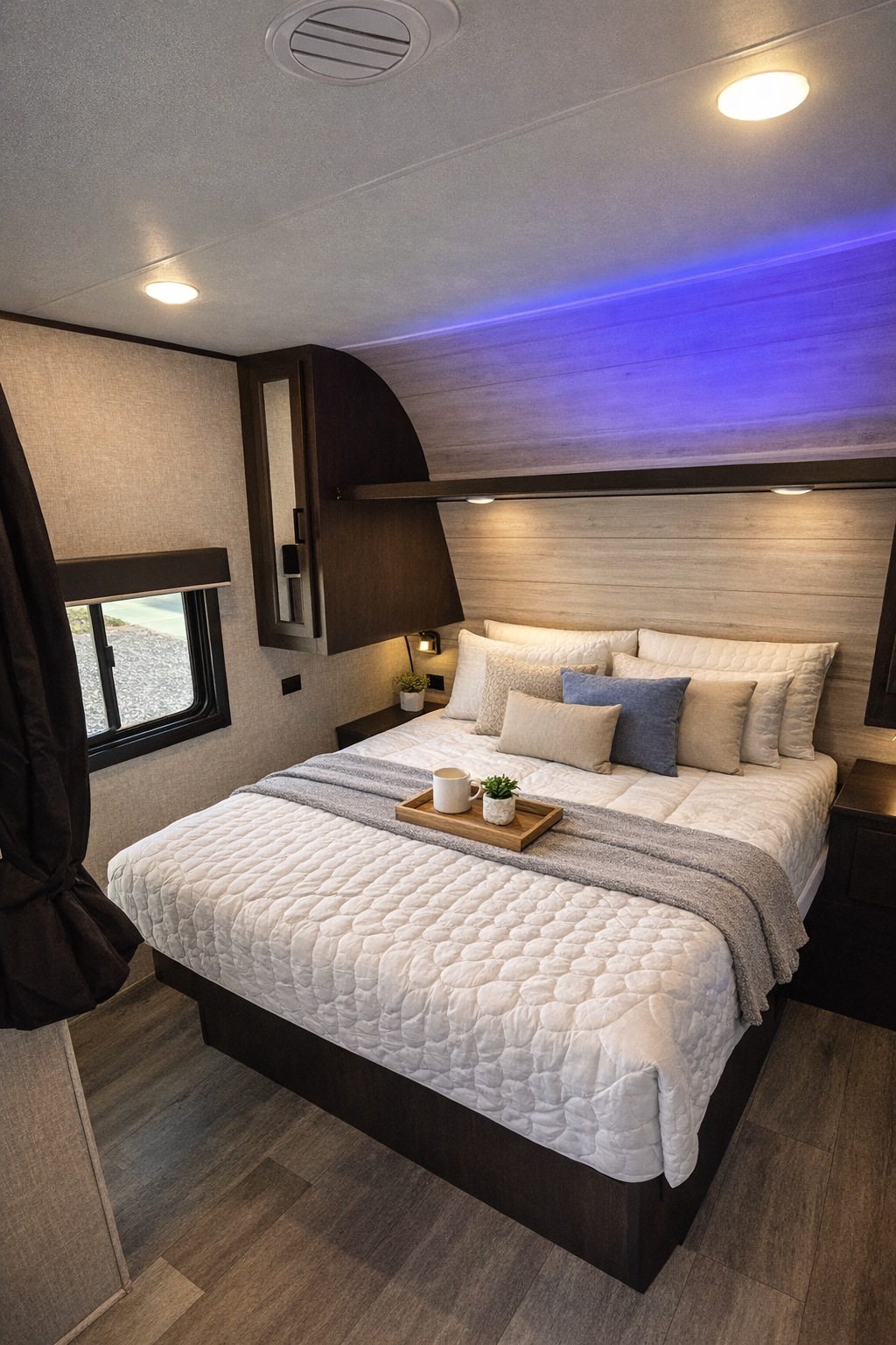 Cozy RV rental bedroom featuring a queen bed with quilted bedding, window, and stylish blue LED accent lighting. Ideal for travel.. Jayco Jay Flight 2022