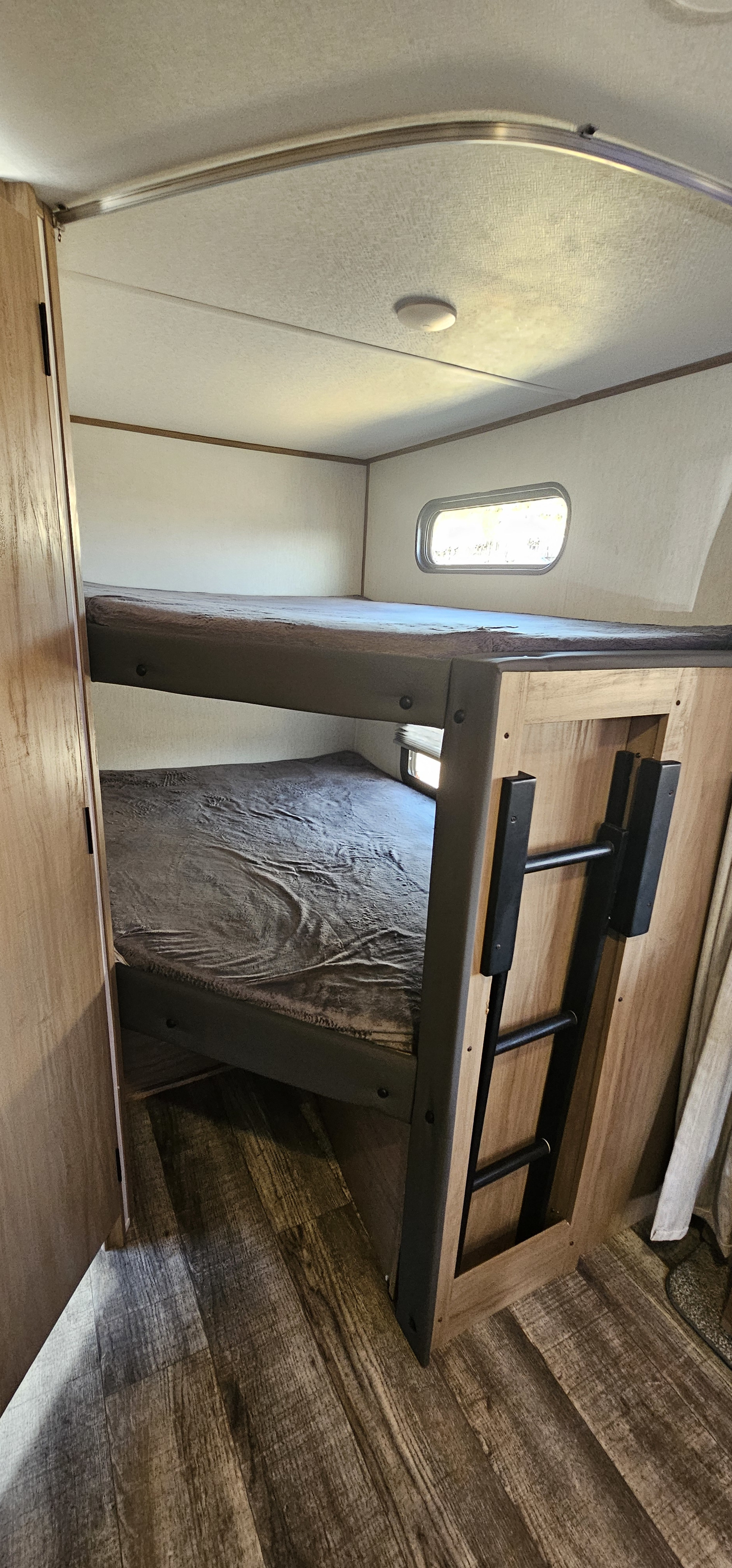 Cozy bunk beds with a ladder & window in this RV rental, offering extra sleeping space inside the camper.. Forest River Cherokee Alpha Wolf 2023