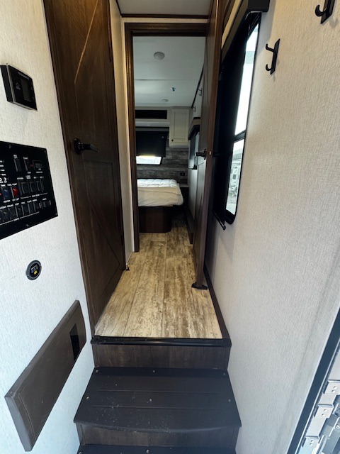Inside this RV rental: steep steps lead up to a hallway with control panels, offering a peek into the cozy bedroom area ahead.. Forest River XLR Nitro Toy Hauler 2022