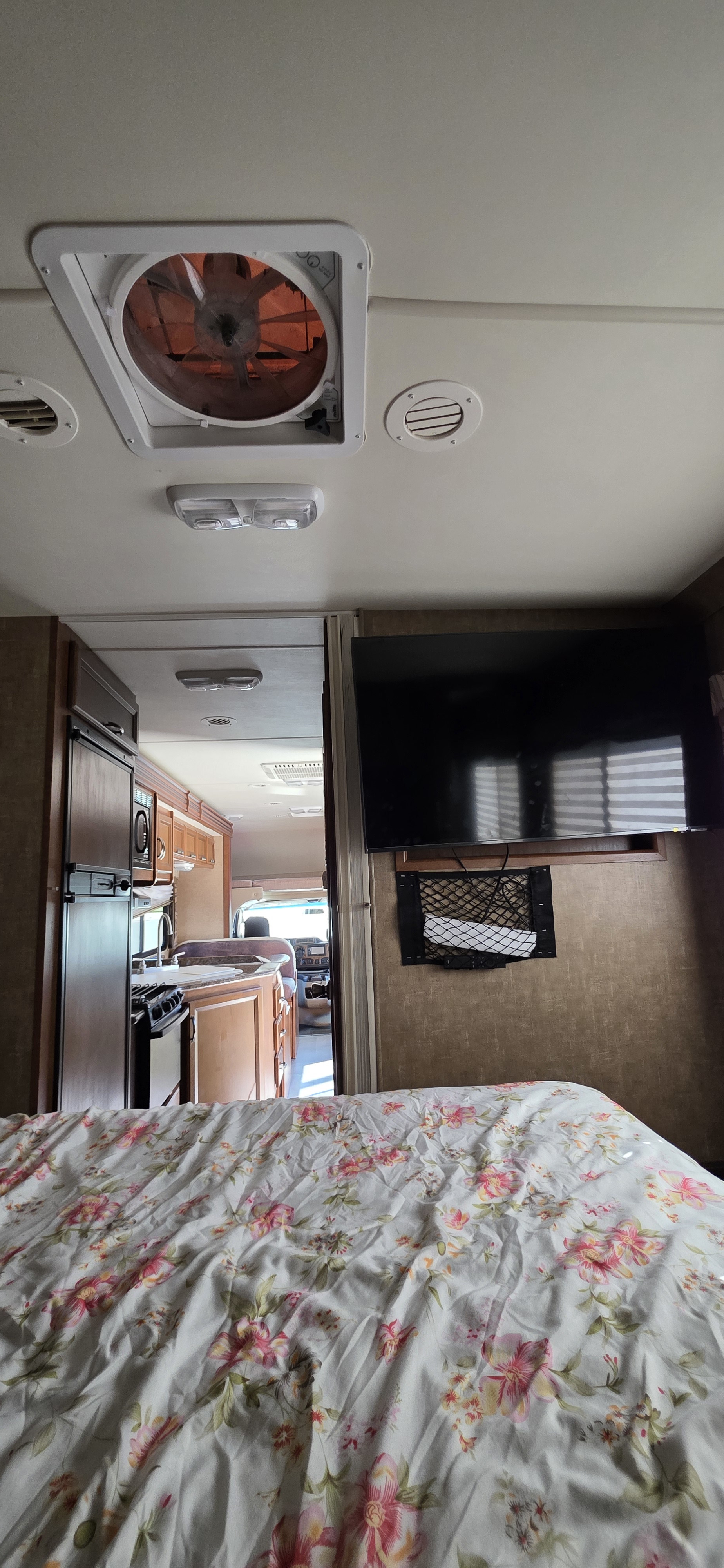 Spacious RV rental interior with a floral bed, kitchen, TV, and cab view, ideal for comfortable travels.. Thor Chateau 2014