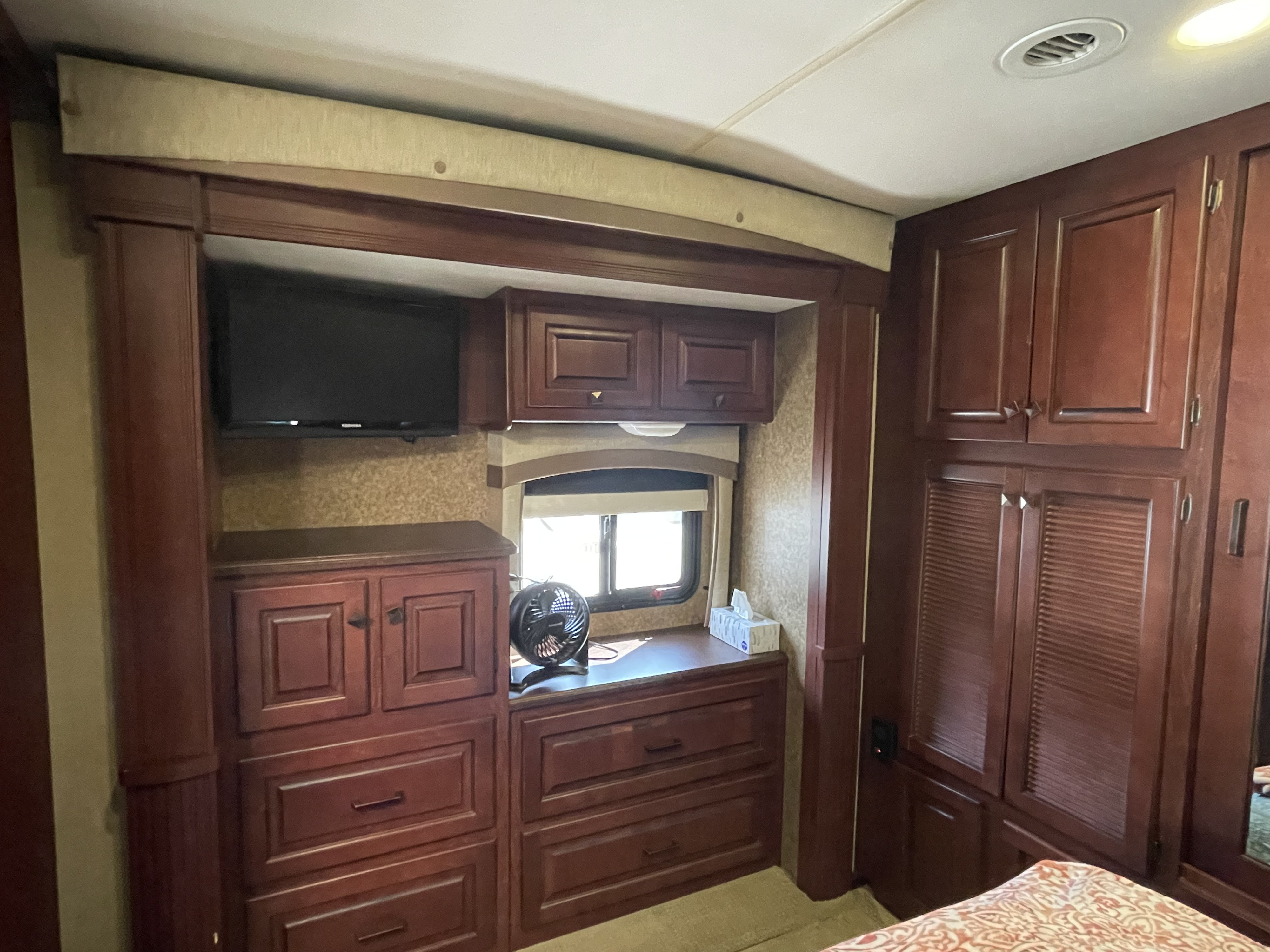 RV rental bedroom: dark wood cabinetry, TV, window, and storage. Cozy and functional space for travelers.. Berkshire Berkshire Motorhome 2013
