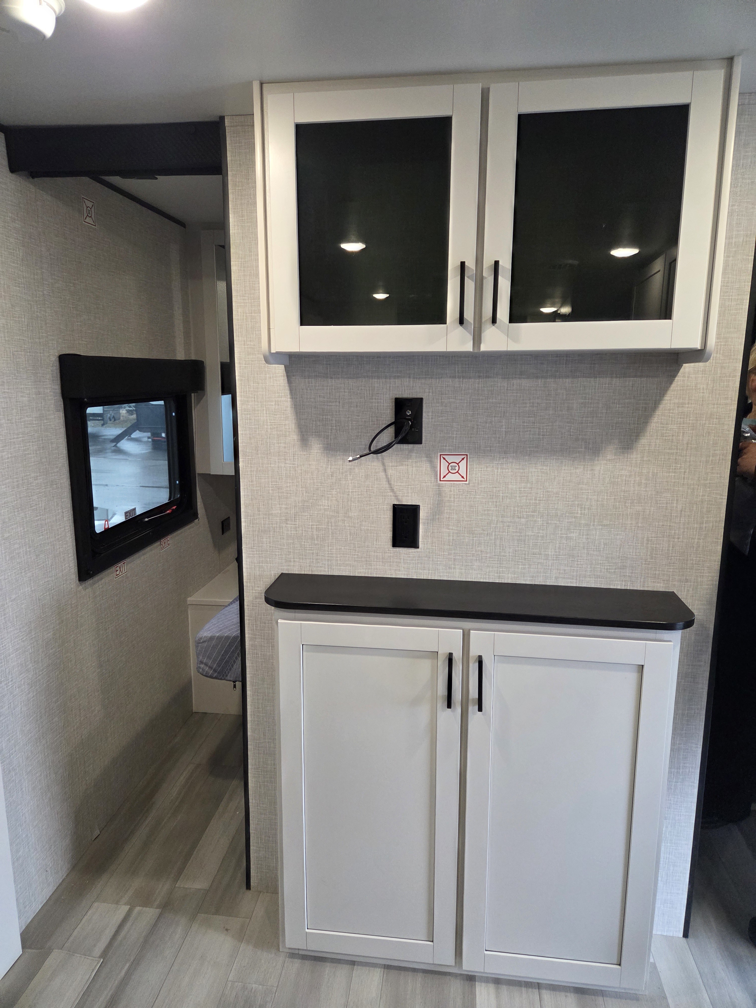 Clean rv rental interior features white glass-front upper cabinets, dark counter, textured walls, and a peek at a bunk area.. Open Range Conventional 26BHS Travel Trailer 2025