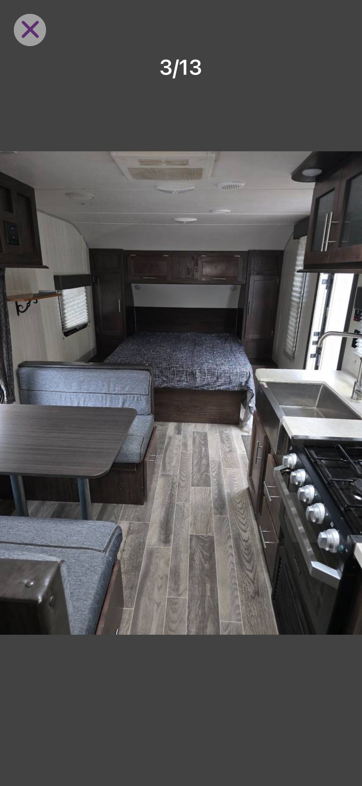 RV rental interior with a bed, dinette, and kitchen. Features wood-look flooring, offering a functional living space.. Forest River Cherokee Grey Wolf 2019