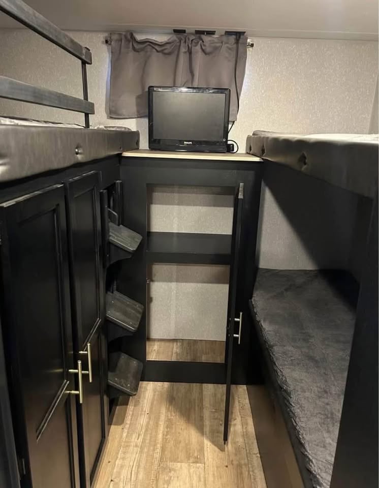 This cozy RV rental interior features compact bunk beds, a TV, and storage cabinets, perfect for a comfortable road trip.. Forest River Cherokee Grey Wolf 2022