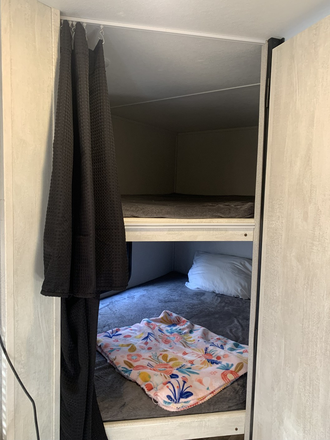 Inside an RV rental: cozy bunk beds with soft bedding and a privacy curtain. Ideal for family camping adventures.. Forest River Shasta 2022
