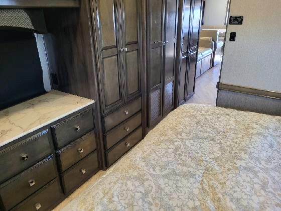 Explore this RV rental's cozy bedroom. Features include a bed, dresser with storage, and cabinets.. Fleetwood Fortis 2020