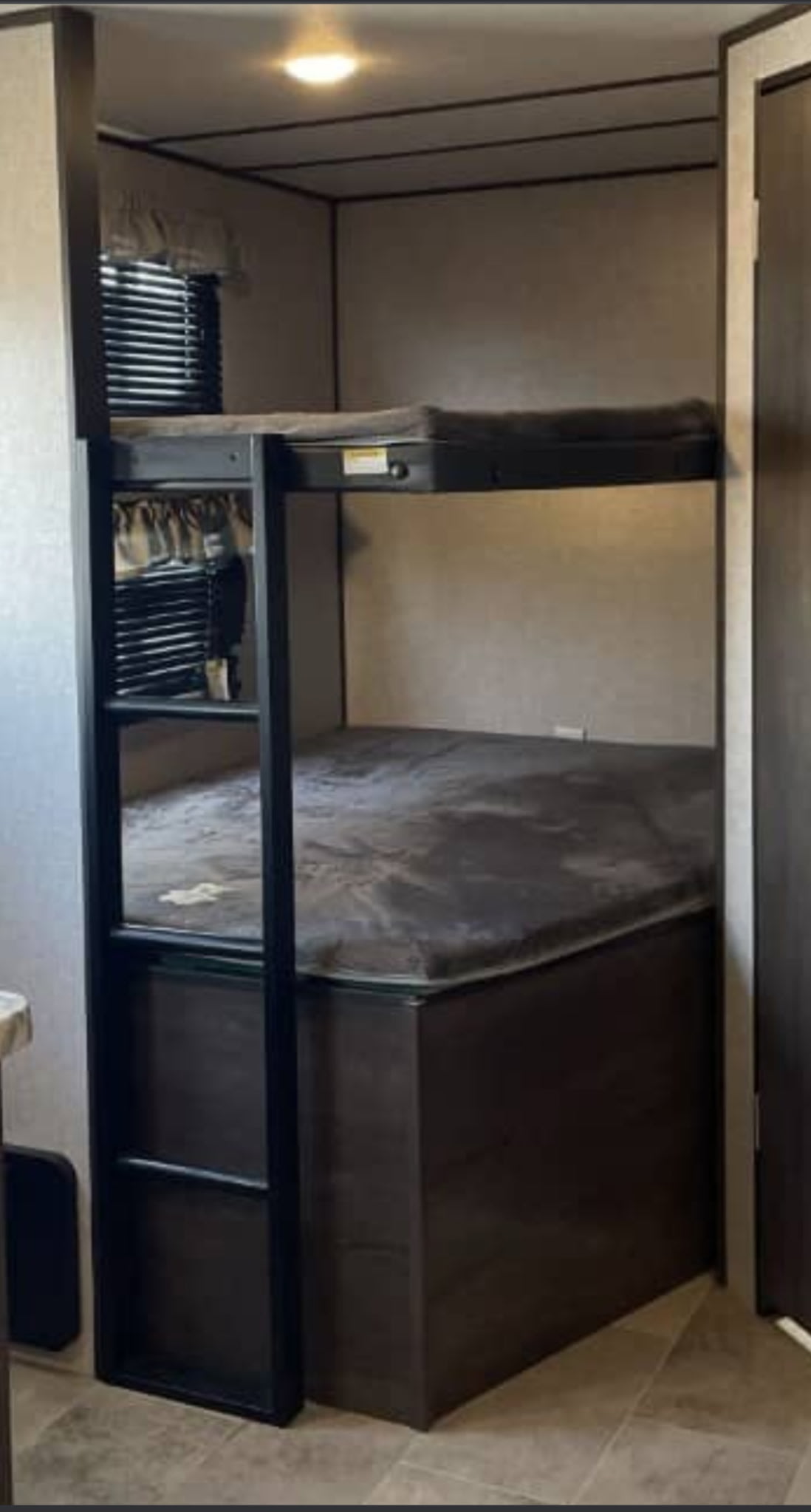 RV rental bunk beds: a cozy sleeping area featuring two beds, a ladder, and a window with blinds.. Dutchmen Coleman Light 2022