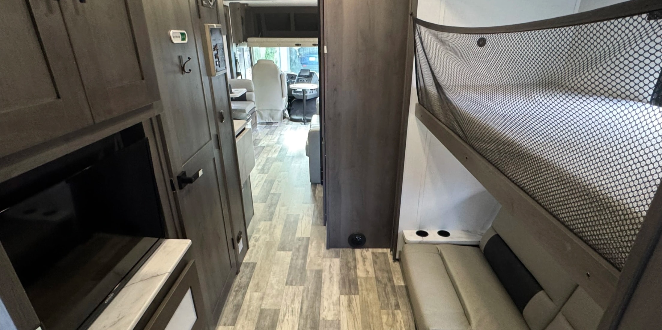 Spacious RV rental interior: hallway to driver's cab, bunk beds with safety net, built-in TV and storage cabinetry.. FR3 FR3 Motorhome 2023