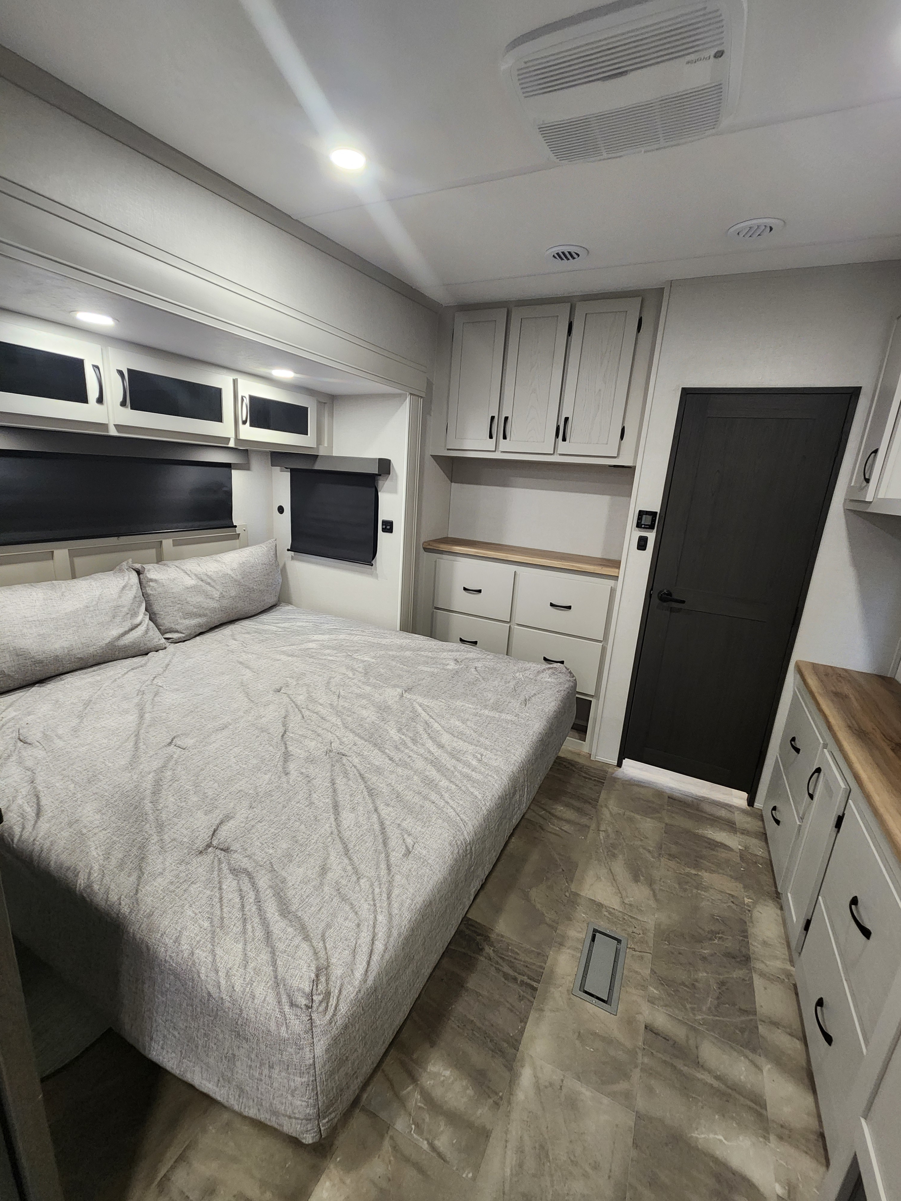 Bright RV rental bedroom with a large bed, light wood cabinets, black window shades, and an AC unit for comfort.. phoenix 334FL 2026