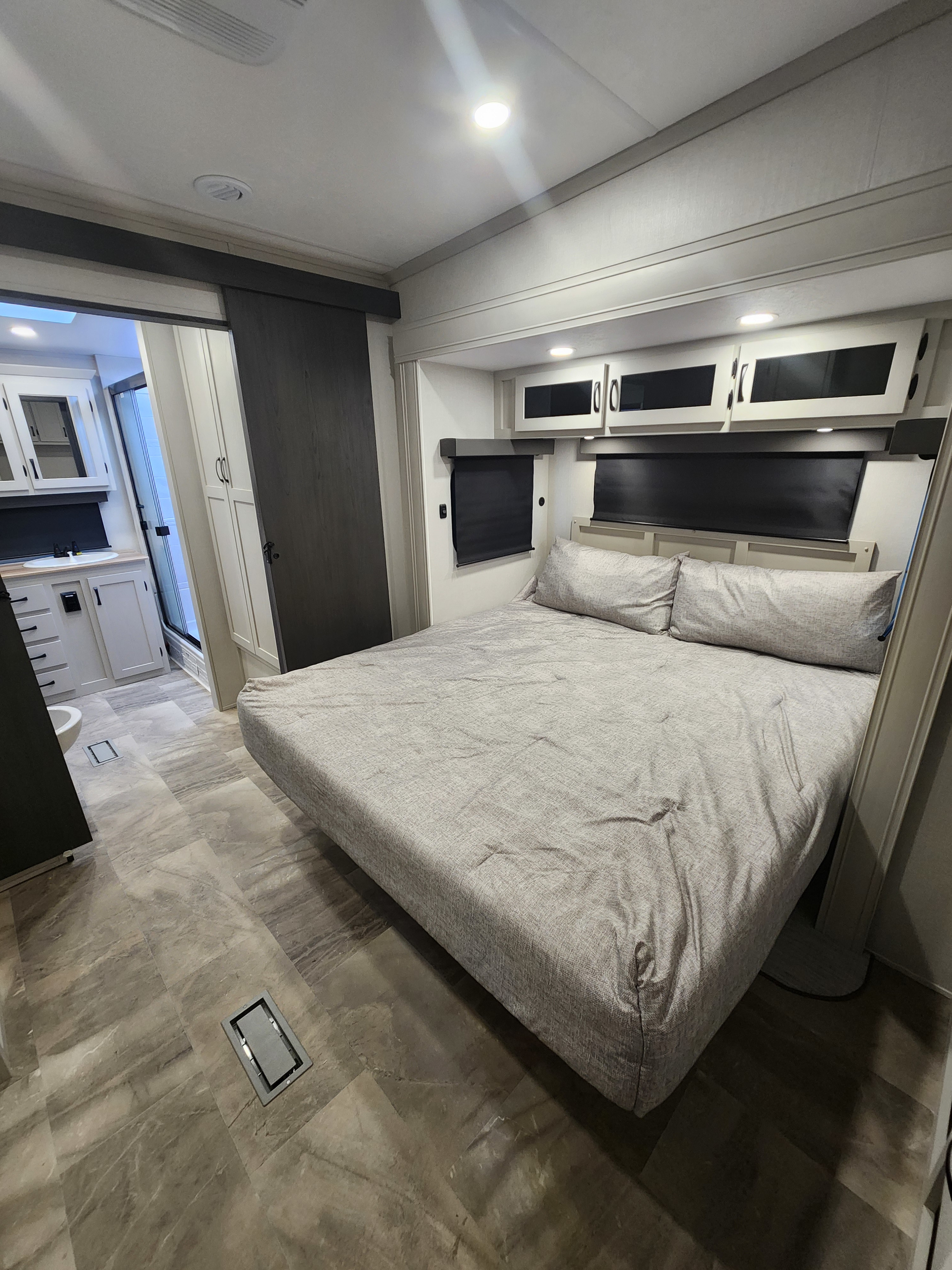 RV rental: modern bedroom featuring a queen bed, overhead cabinets, and a connected bathroom with vanity & shower.. phoenix 334FL 2026