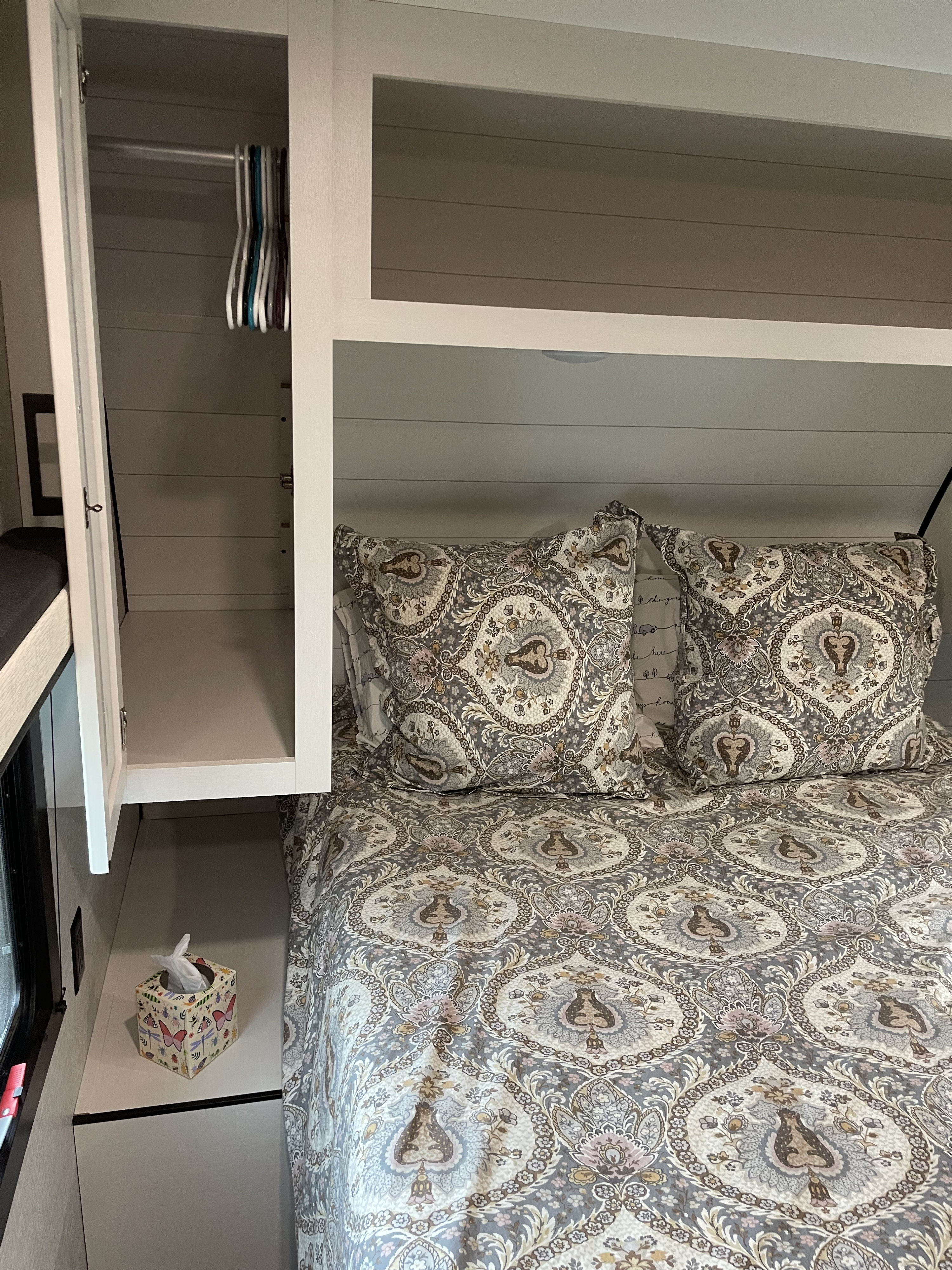 Cozy RV rental bedroom with paisley bedding, pillows, and open wardrobe with hangers for a comfortable stay.. Jayco Jay Flight 2024