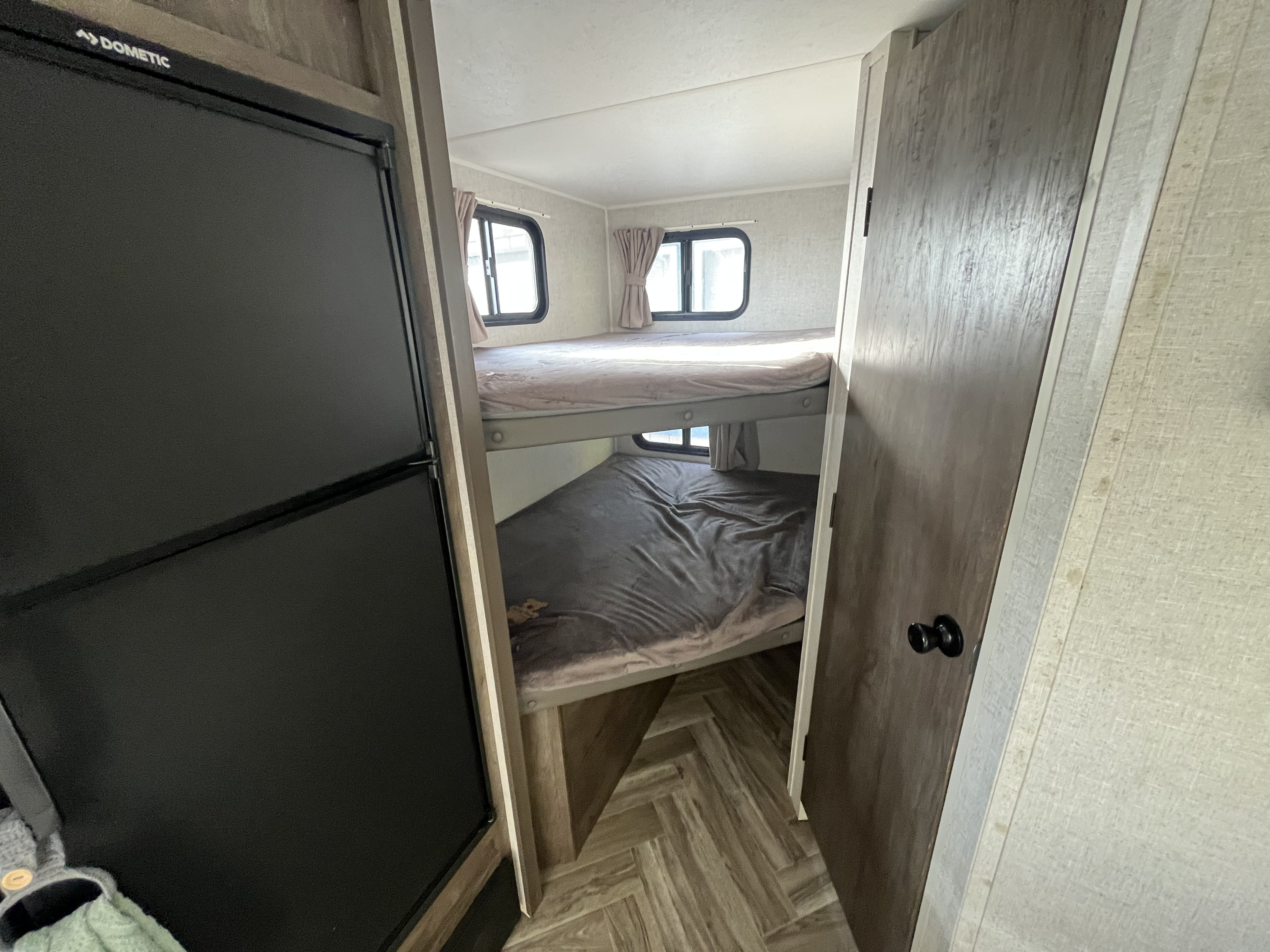 RV rental interior featuring bunk beds with windows and a Dometic refrigerator, offering a compact sleeping area.. Forest River Salem FSX 2021