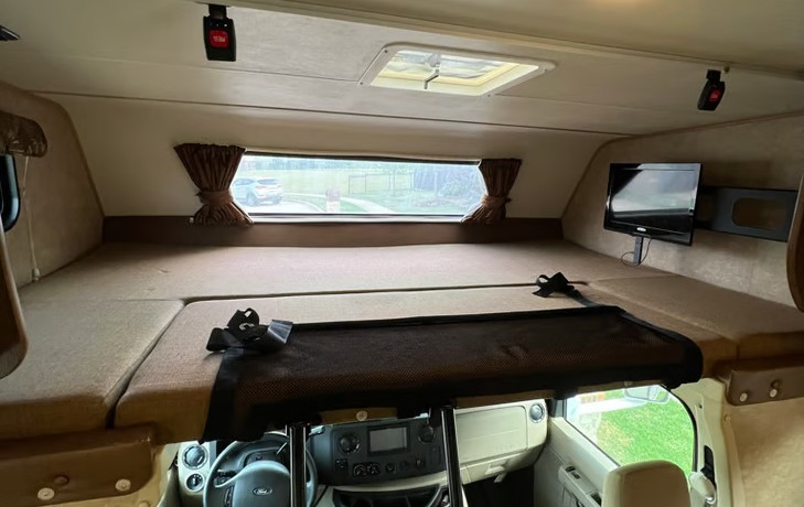 Spacious over-cab bunk bed with safety net, window, skylight, and TV in an rv rental. Ideal extra sleeping space.. Coachmen Leprechaun 260QB 2016