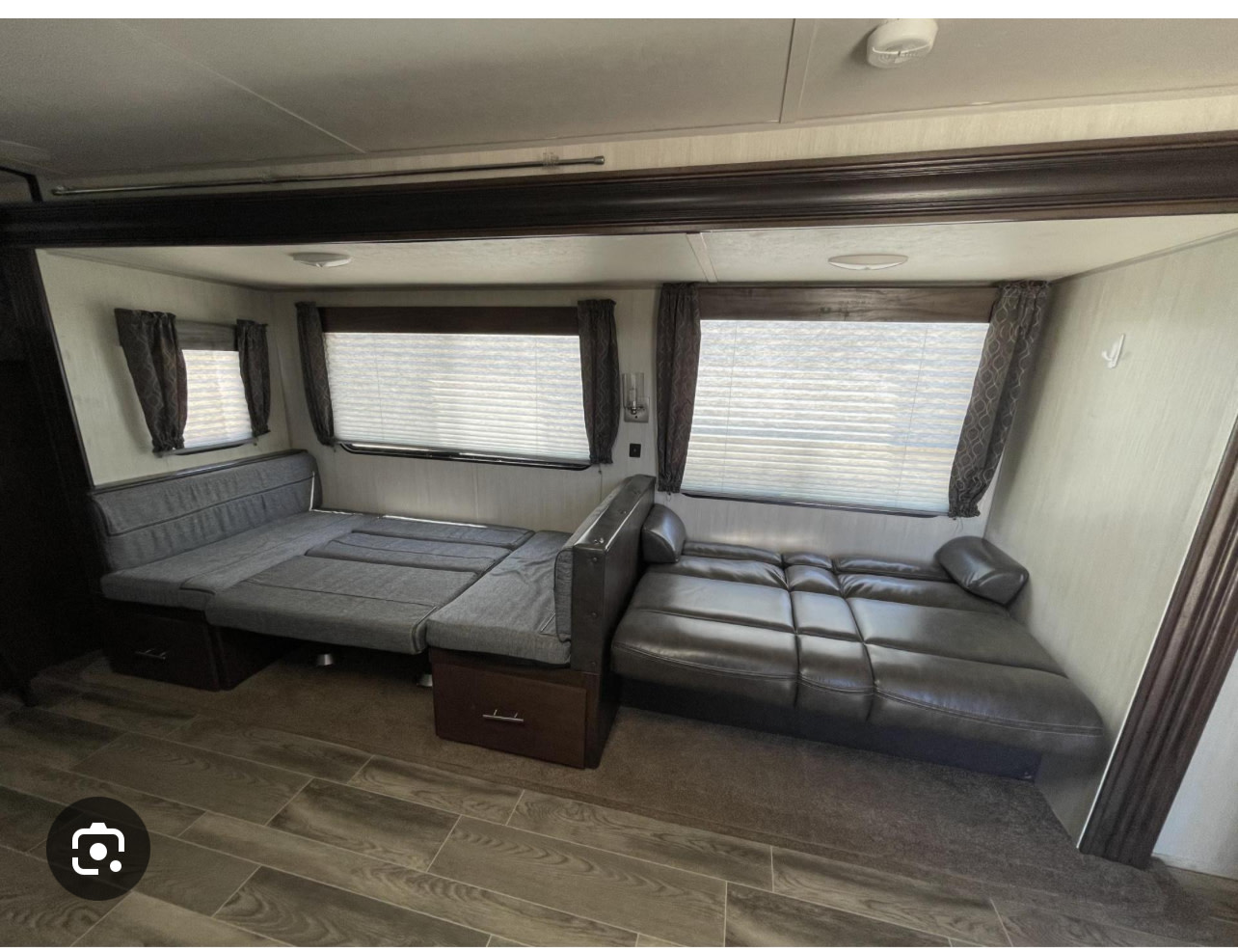 RV rental interior shows two convertible beds: a gray fabric dinette and a leather-look sofa for versatile living.. Forest River Cherokee 2019